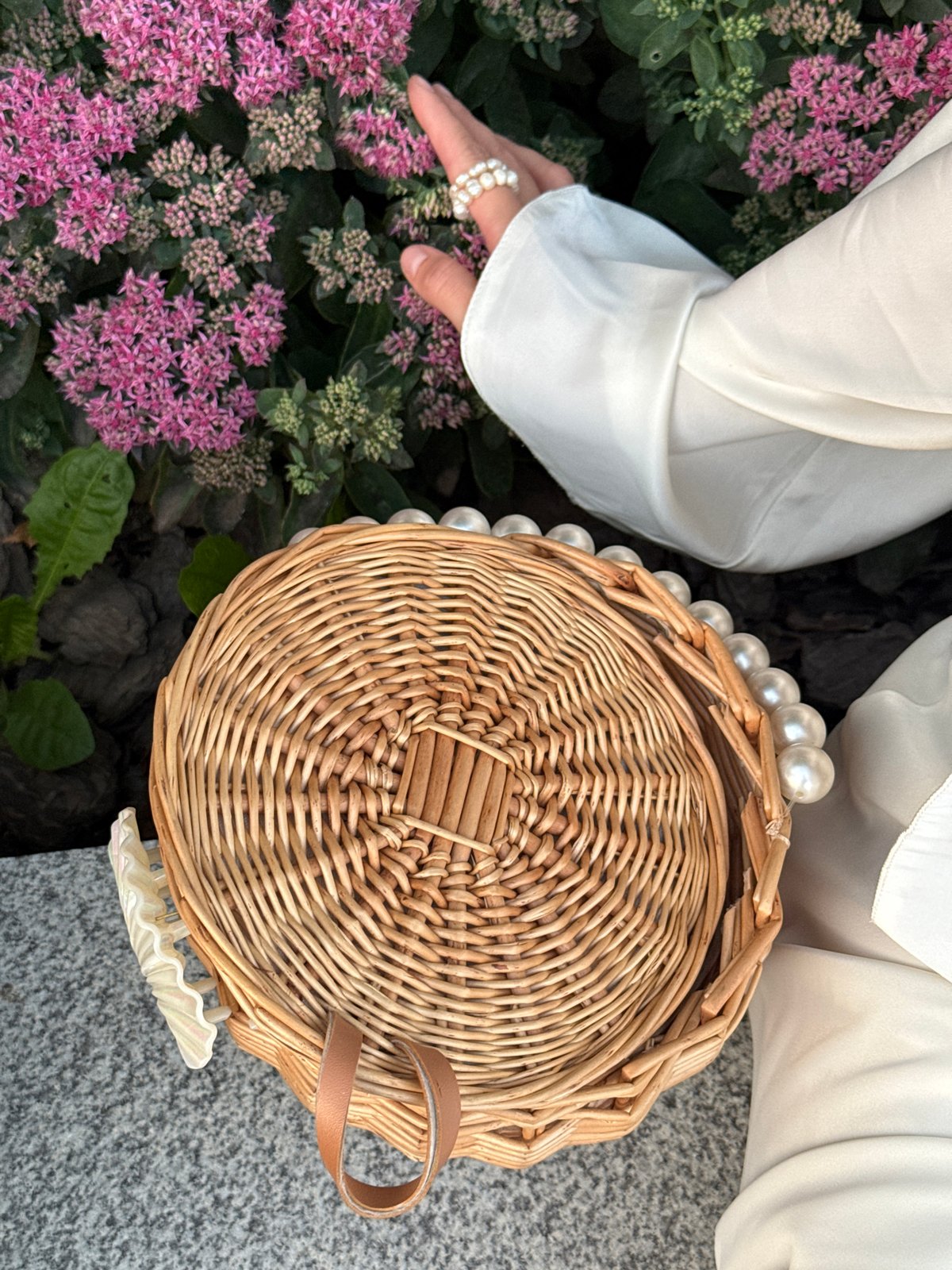 Pearl-adorned woven basket on a grey stone surface