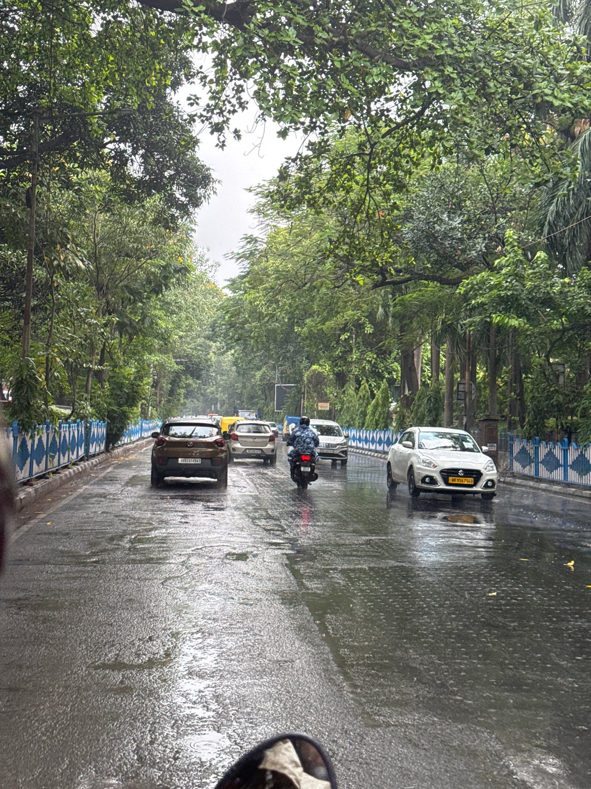 Motorcyclist navigates wet Kolkata streets during morning rain