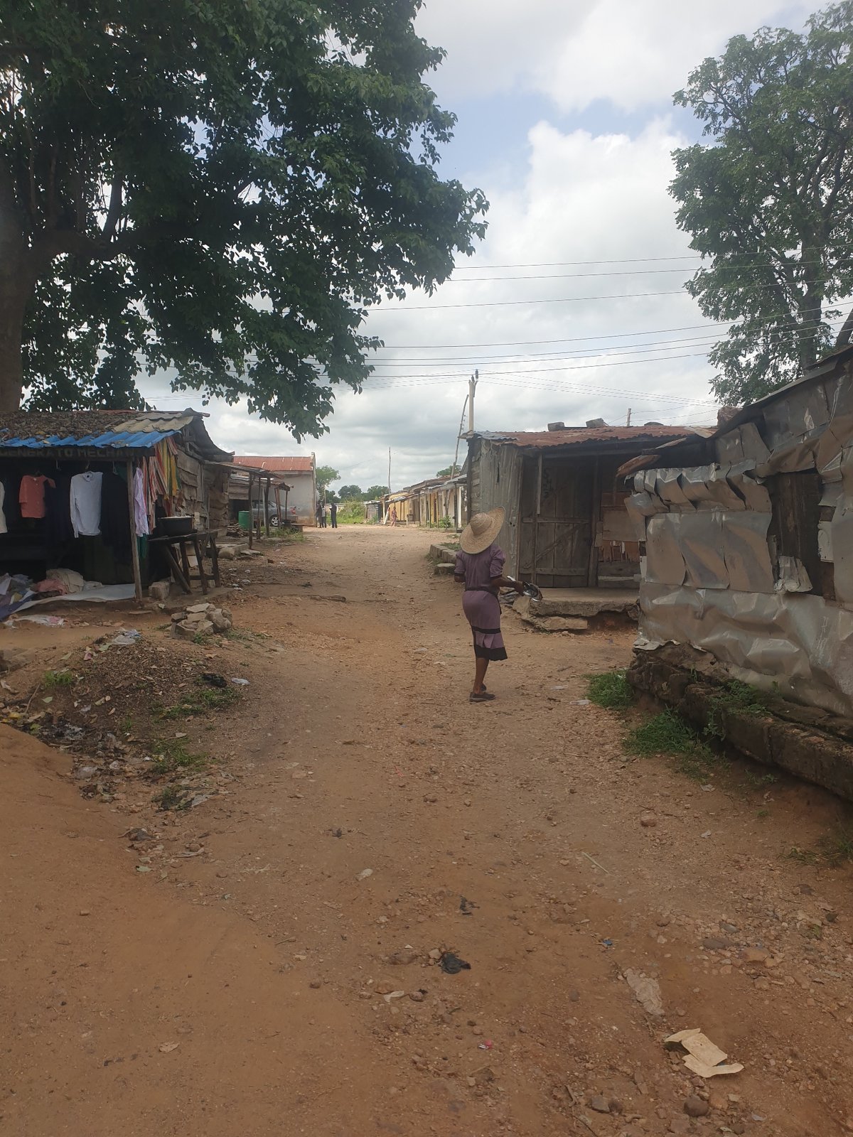 Person with bicycle walks dirt road in developing area