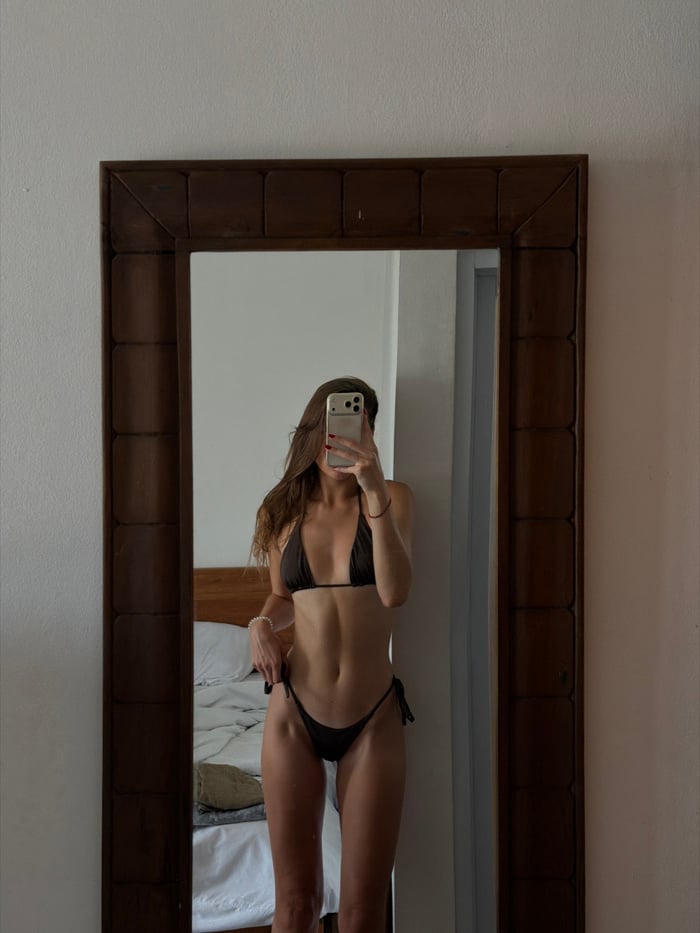 Woman takes mirror selfie in bikini in Tibubeneng room