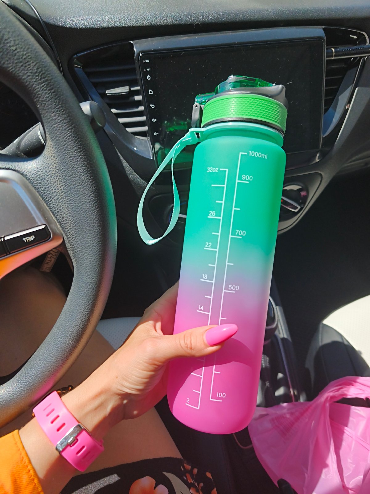 Person with pink smartwatch holds water bottle in Hyundai car