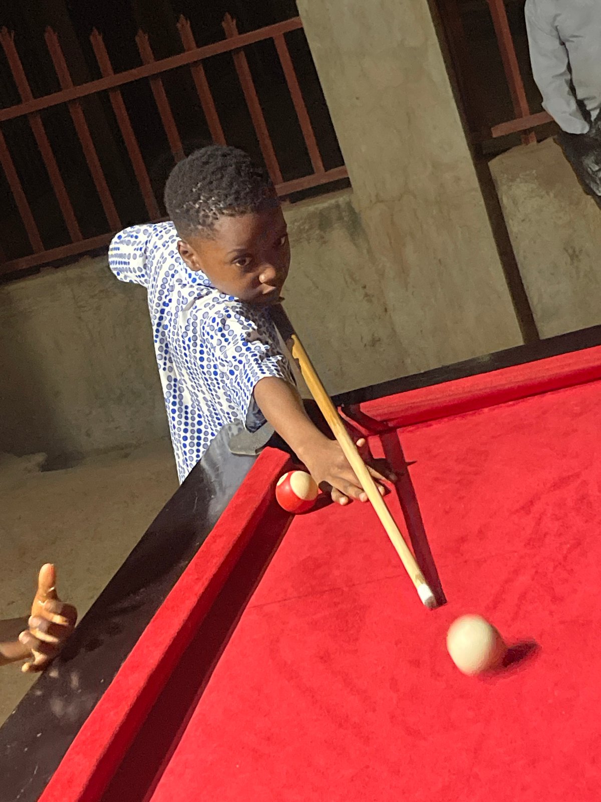 Boy plays outdoor billiards in Unguwar Gabas, Nigeria