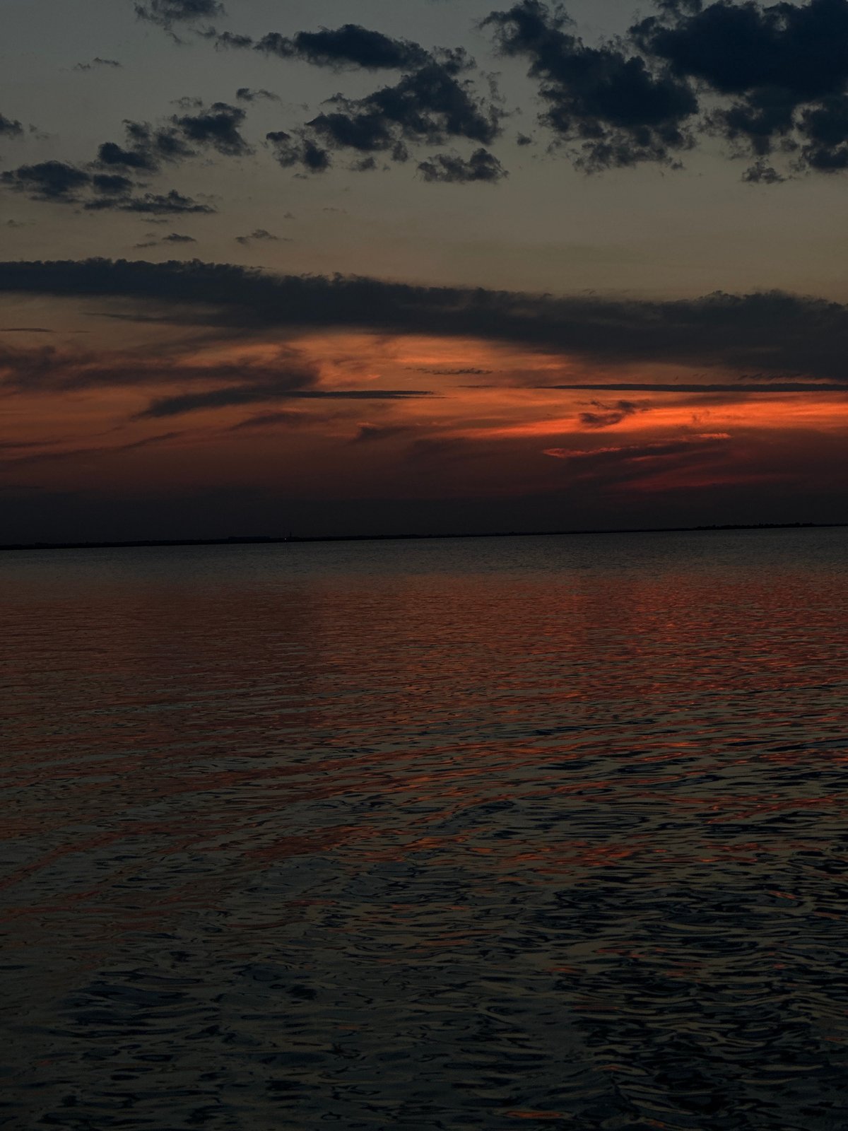 Sunset on a Kokshetau lake, boats and people on the water's edge