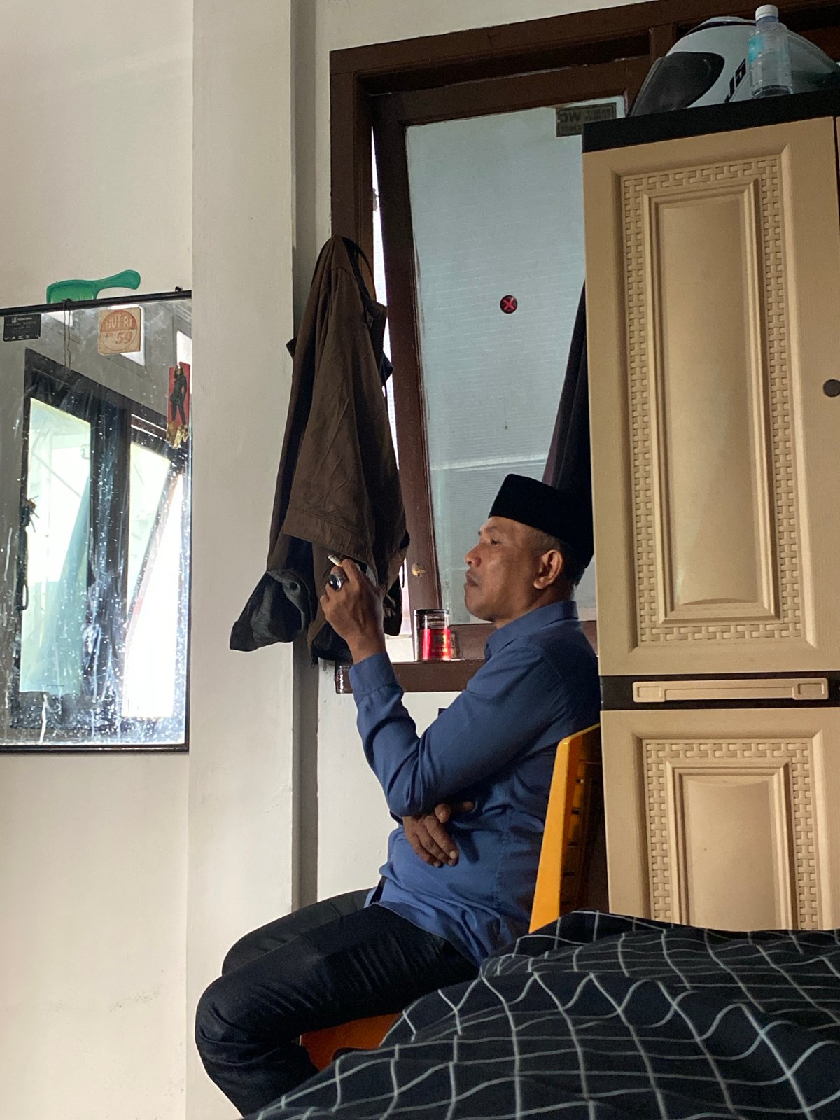 Two people relaxing indoors, one smoking, one resting on a bed.