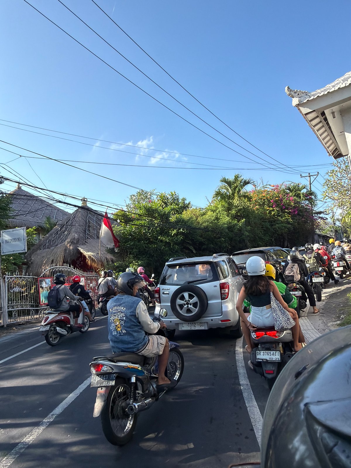 Traffic jam on a North Kuta street, motorcycles and cars at standstill.