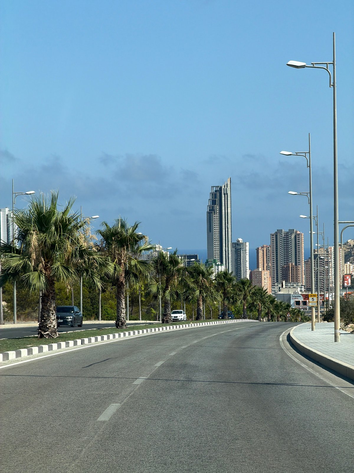 Palm-lined coastal road leading into Finestrat's city skyline