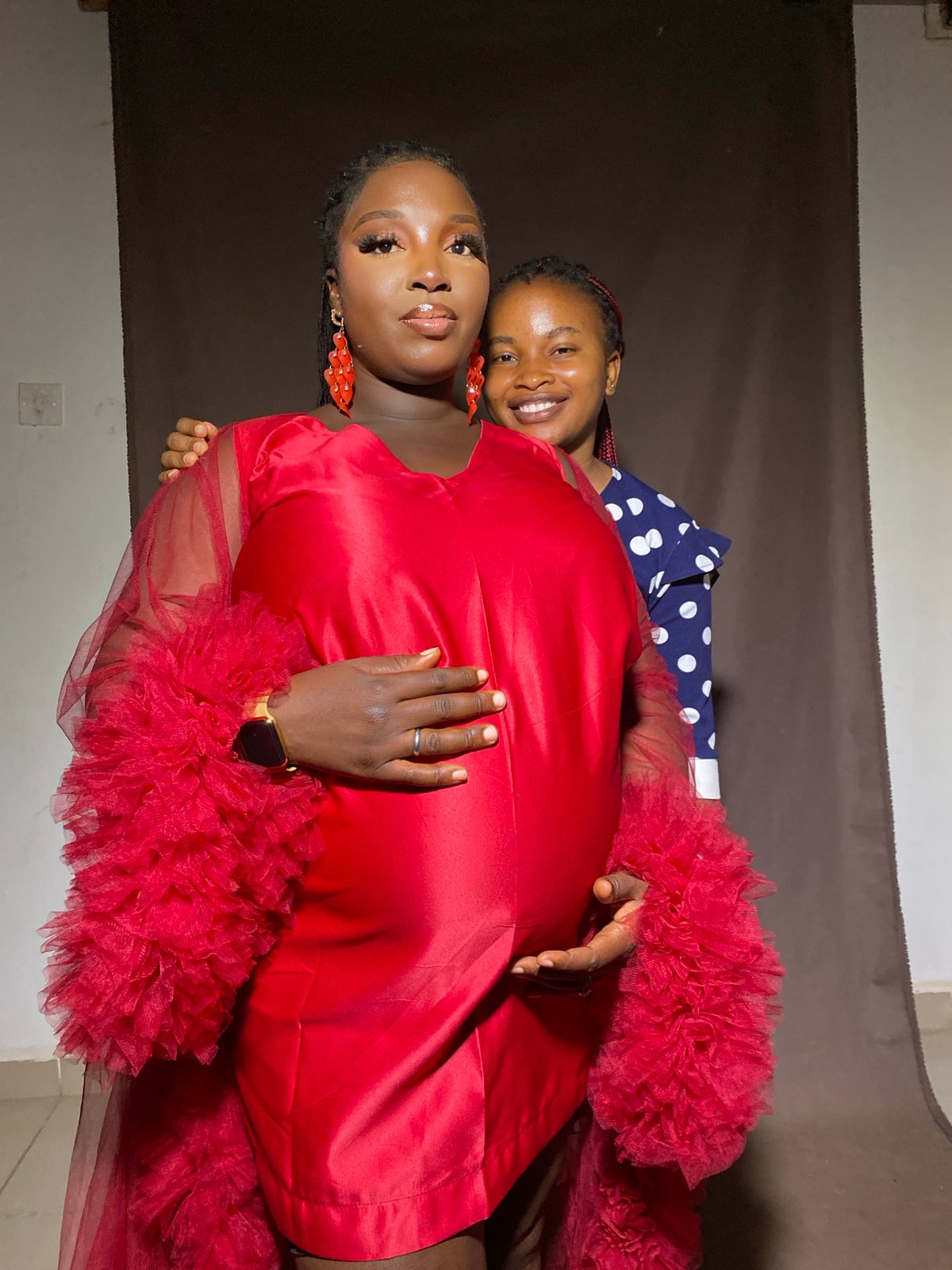 Maternity studio shoot in Jos, Nigeria, red dress and dark backdrop.