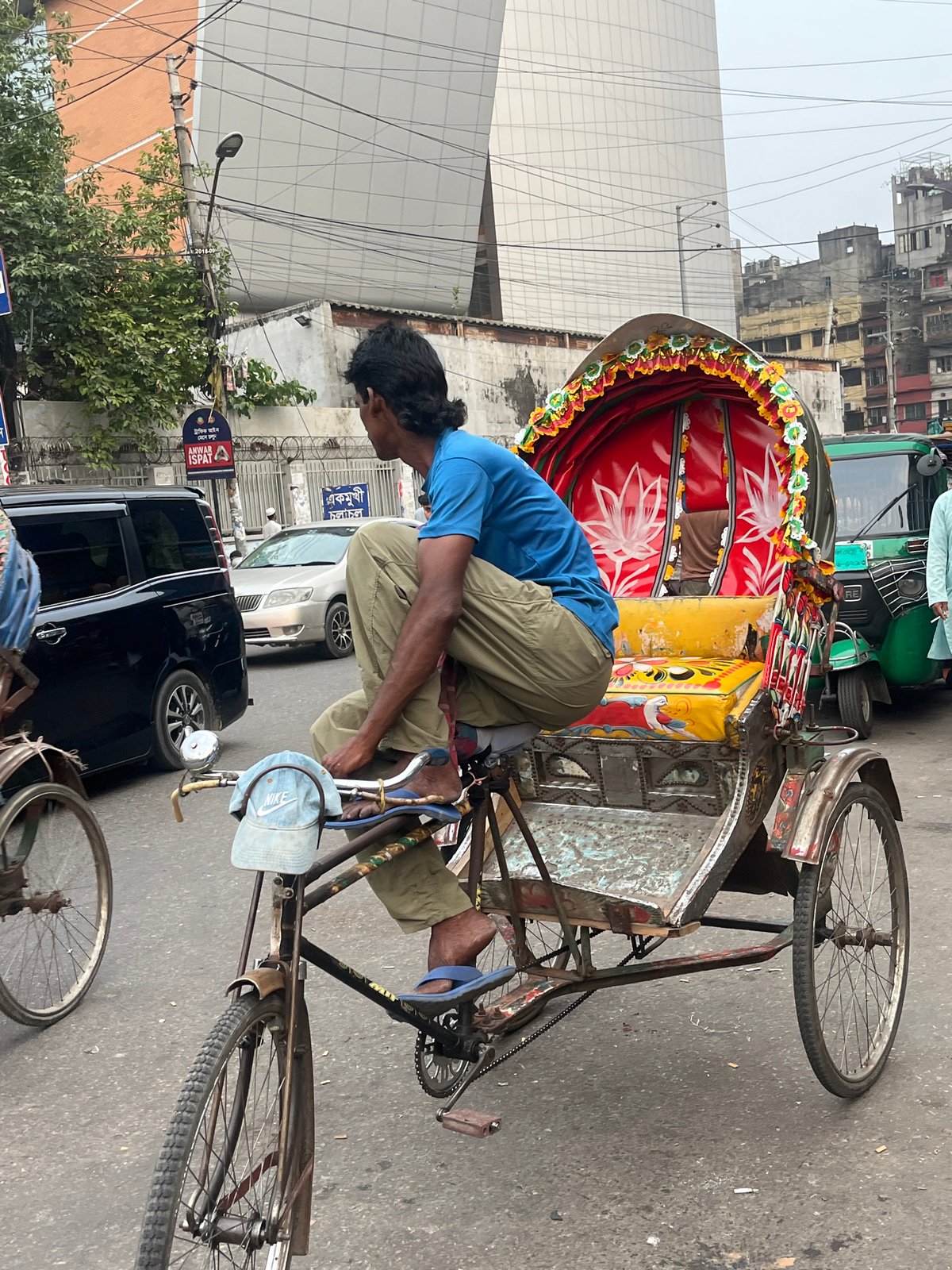 Decorated rickshaw navigates busy Dhaka streets amid typical urban activity