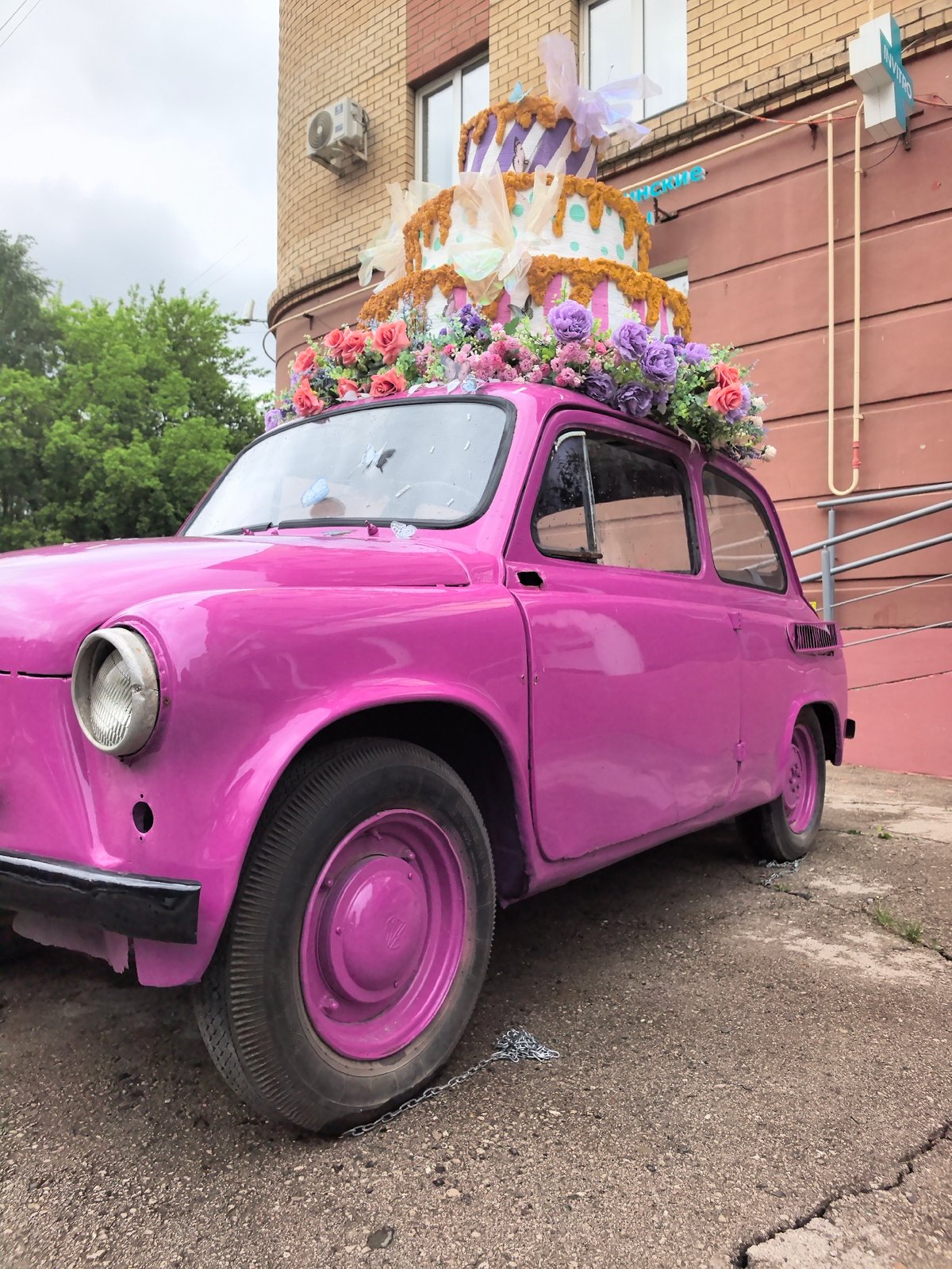 Pink car displays ornate cake on roof
