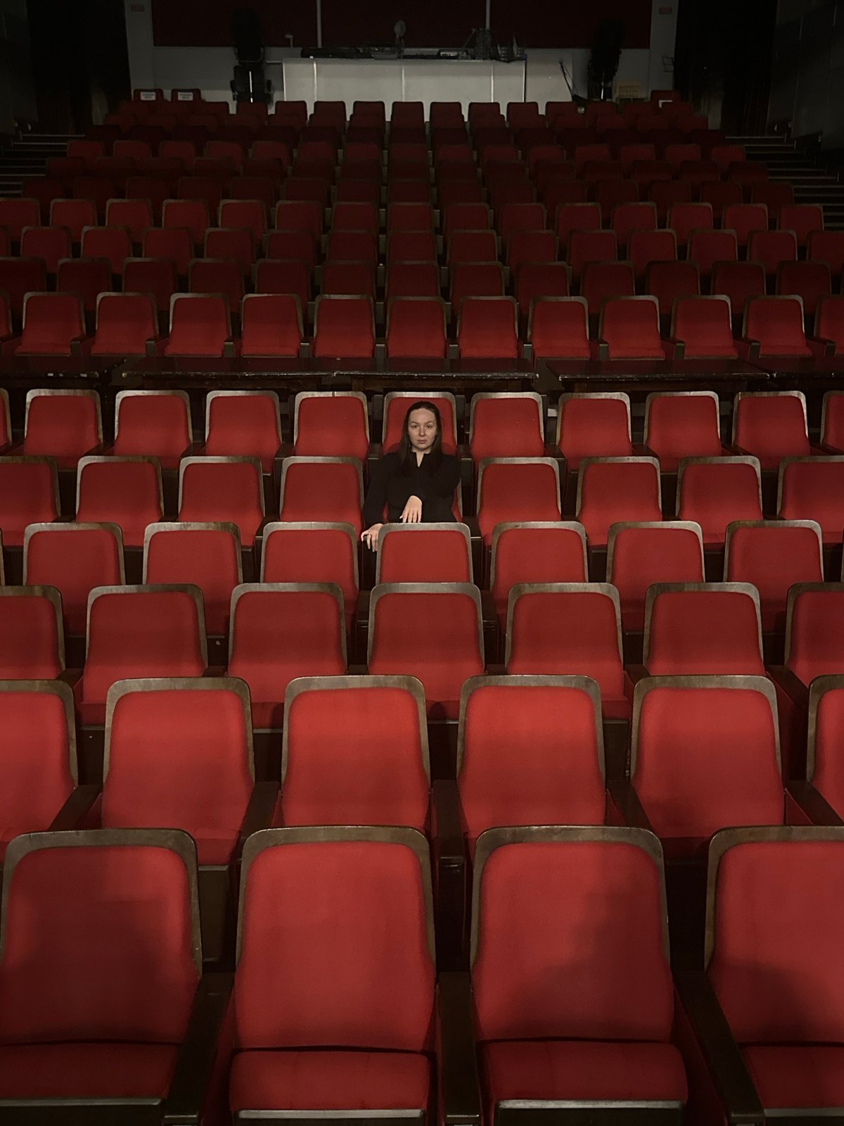 Empty red theater seats fill dimly lit auditorium