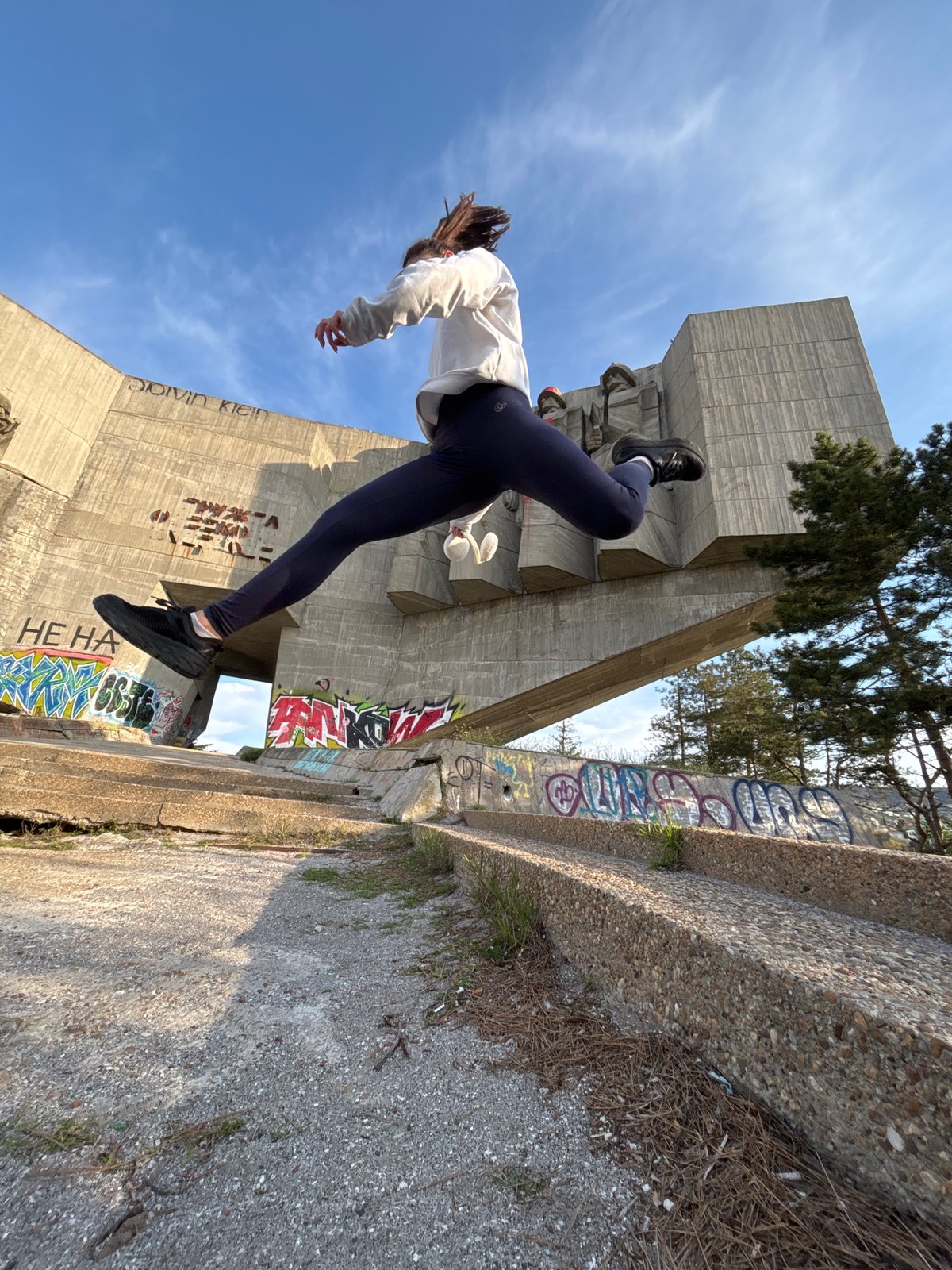 Person exercises near graffitied urban monument