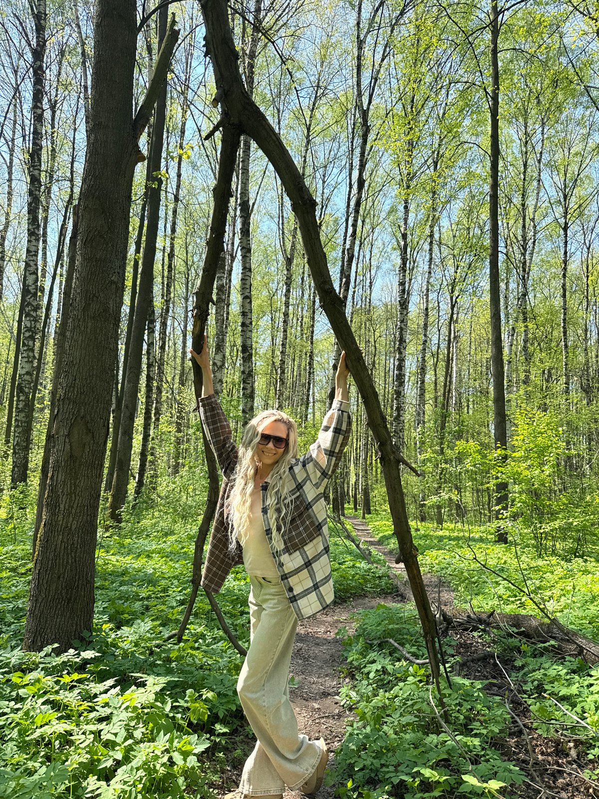 Woman holds fallen branch in sunlit forest