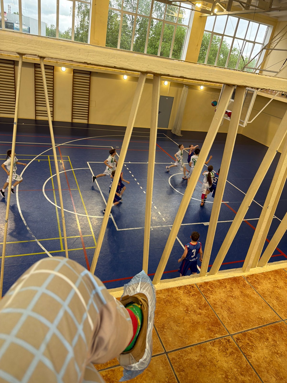 Basketball game viewed from elevated position in Russian gymnasium