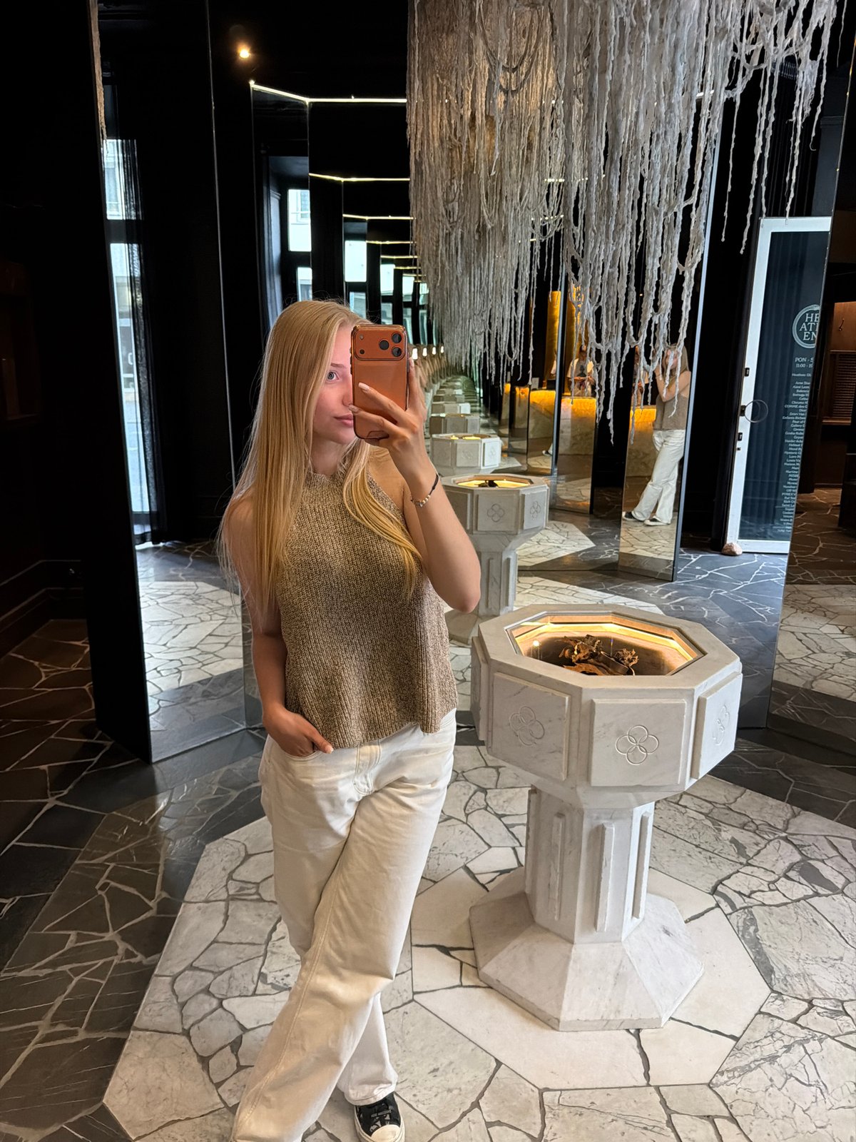 Woman takes mirror selfie in sophisticated mirrored interior space