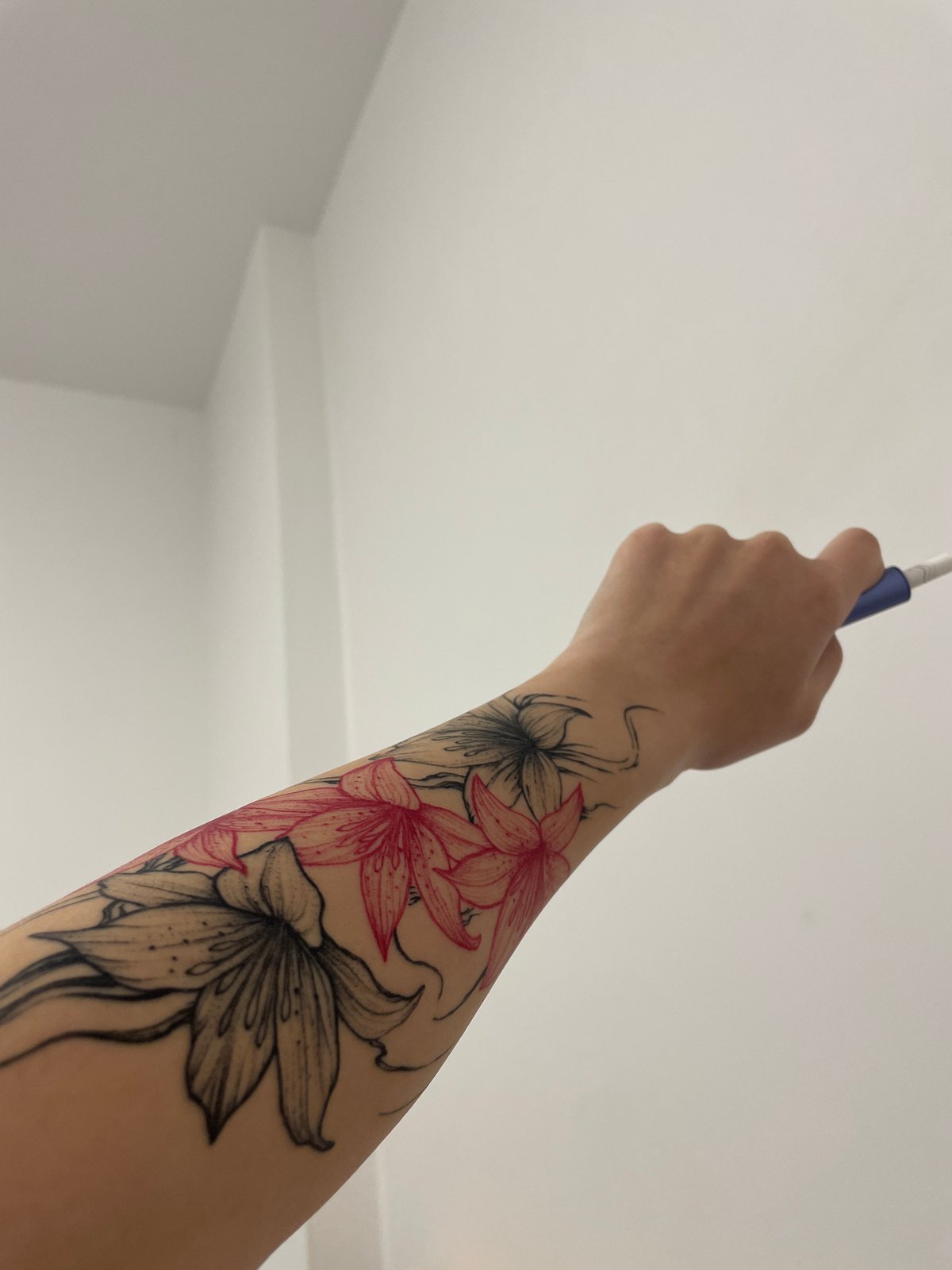 Person with floral tattoo holds electronic device in Sofia