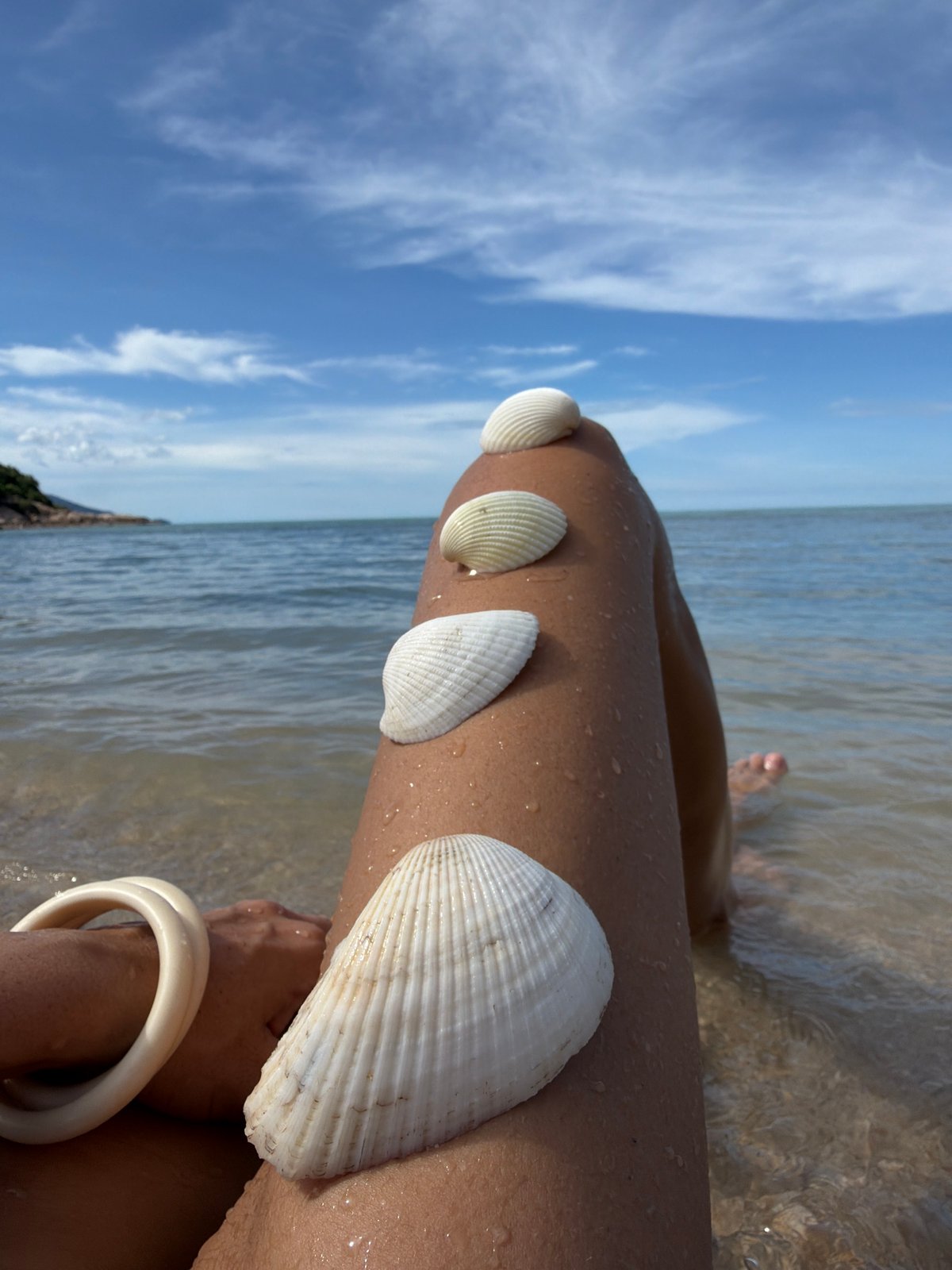 Wine glass, seashells, and shallow water at a Thai beach