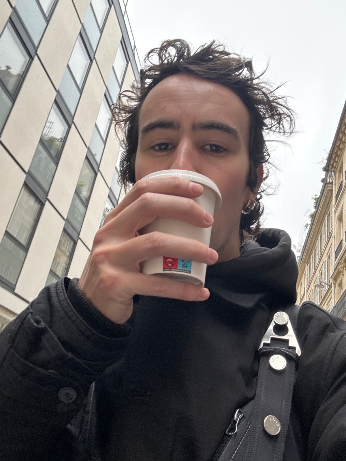 Man drinks from cup on Paris street morning