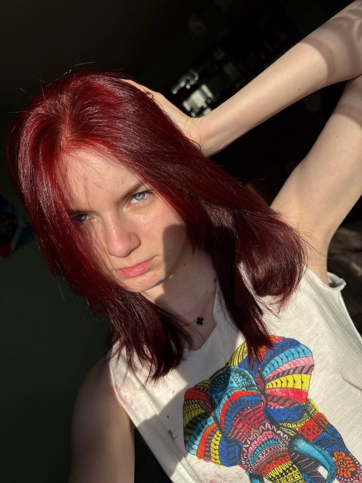 Red-haired woman photographed in bedroom wearing Thailand t-shirt