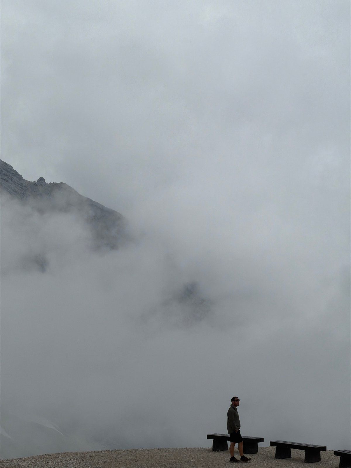 Hikers on a cloudy, snow-patched mountain trail in Wildermieming