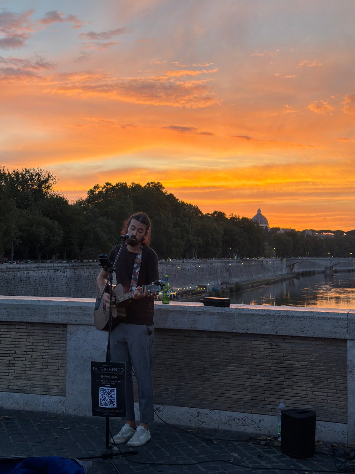 Acoustic busker performs on a bridge at golden hour