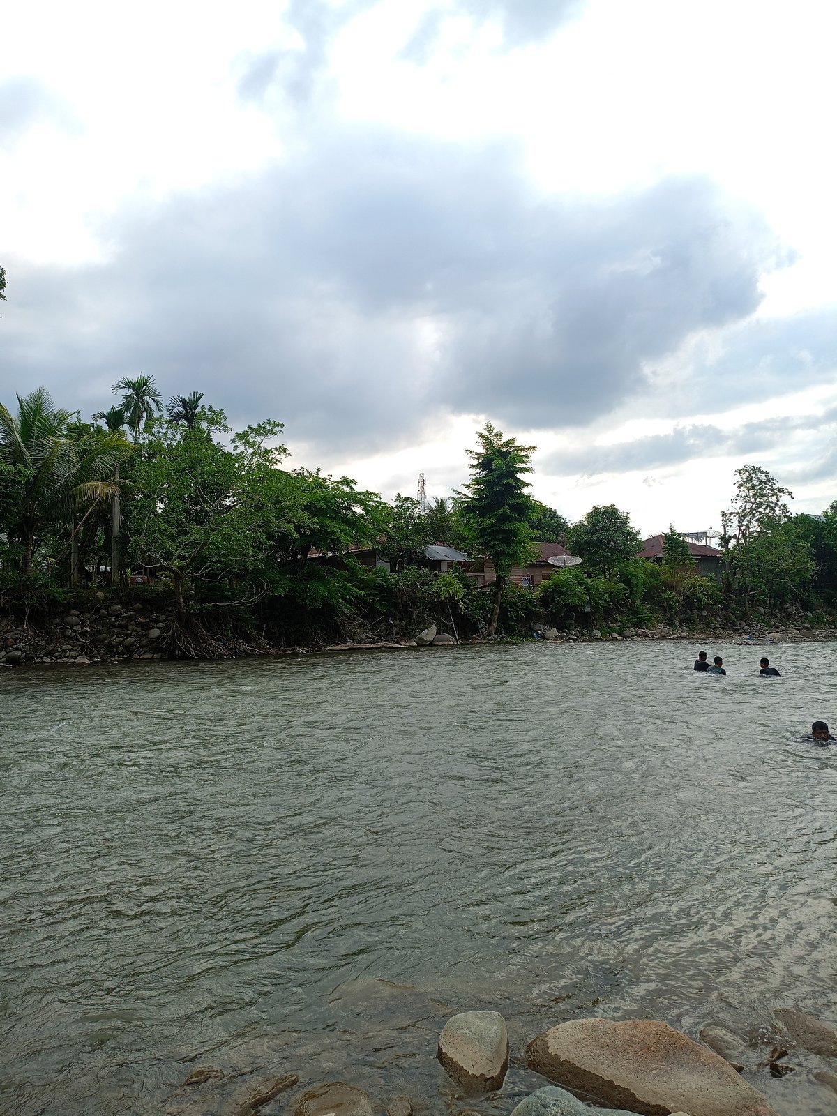 Residents swim in Meurah river during overcast morning