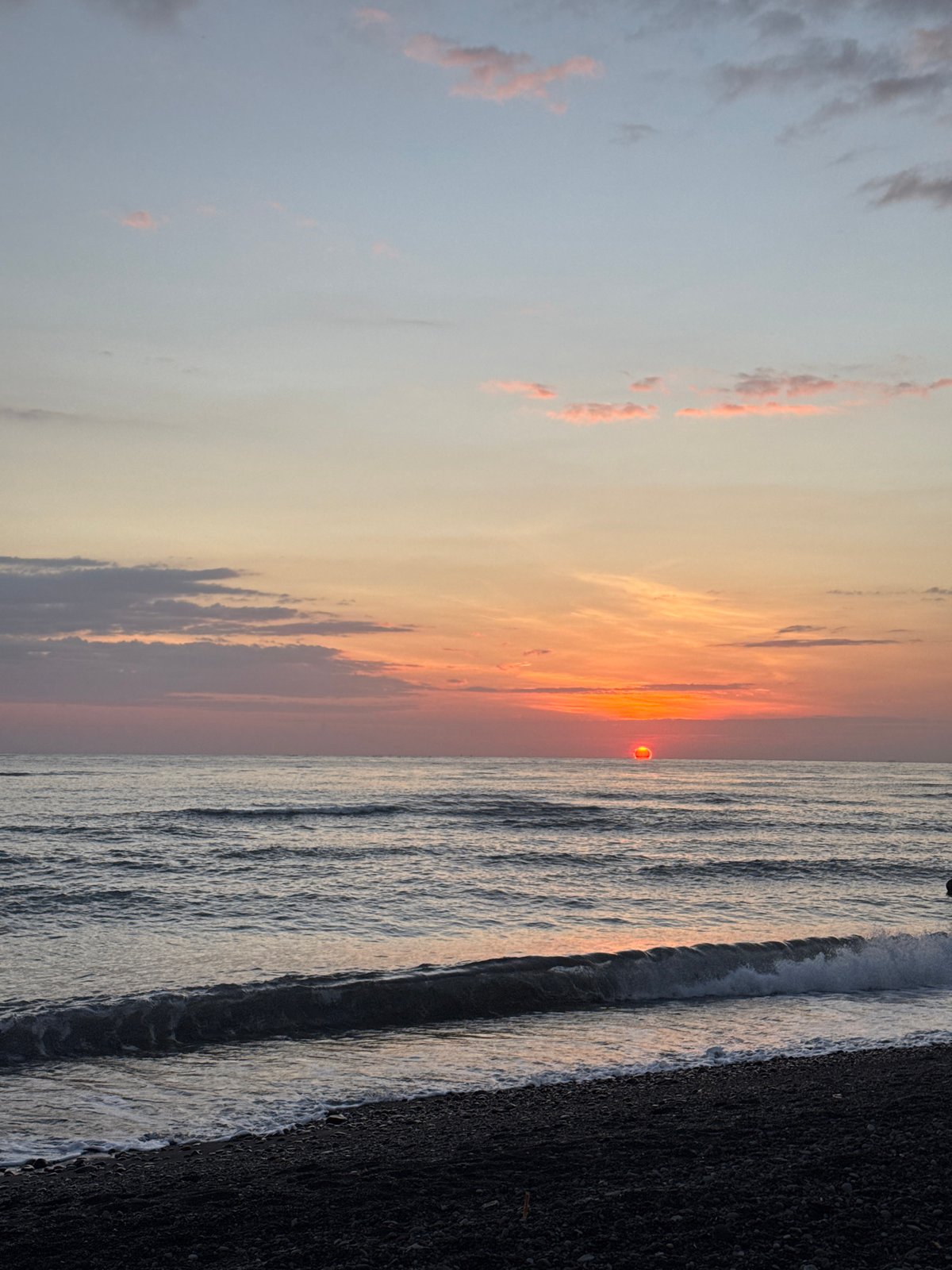 Black pebble beach sunset at a resort in Abang, Bali
