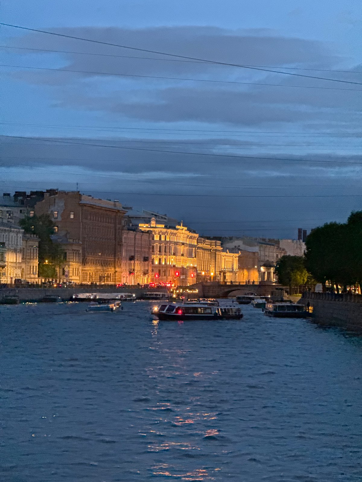 Pink-clad tourist documents evening Saint Petersburg river walk, landmarks