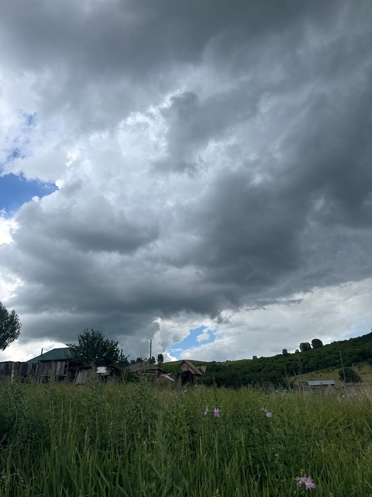 Storm clouds gather over rural Soloneshnoye fields and hills