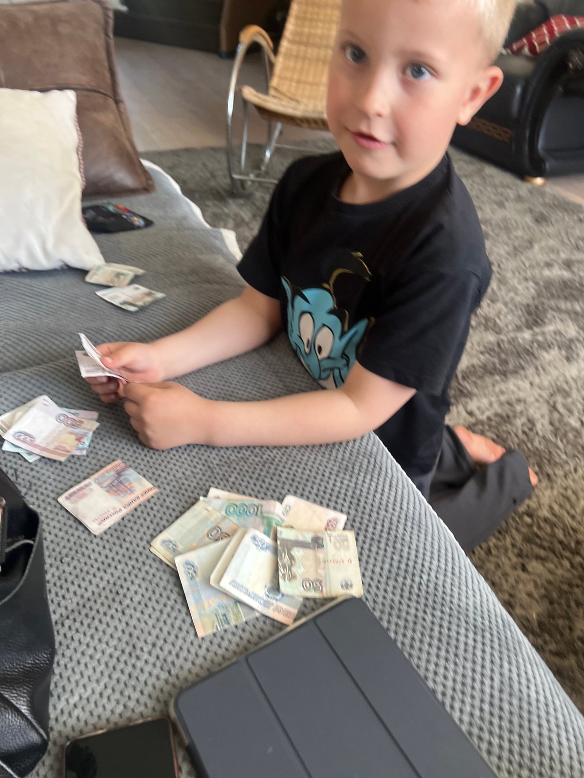 Child counts Russian rubles on sofa during domestic scene