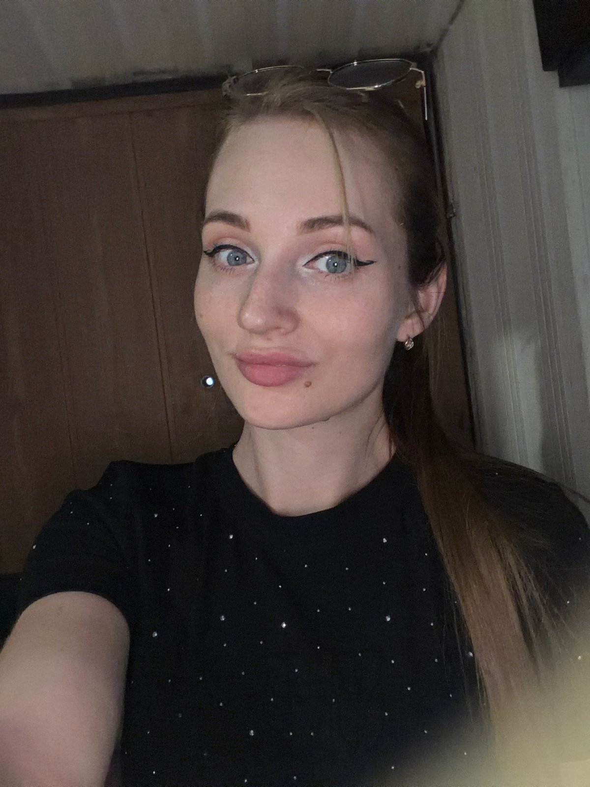 Selfie portrait with winged eyeliner and a sparkly black top.