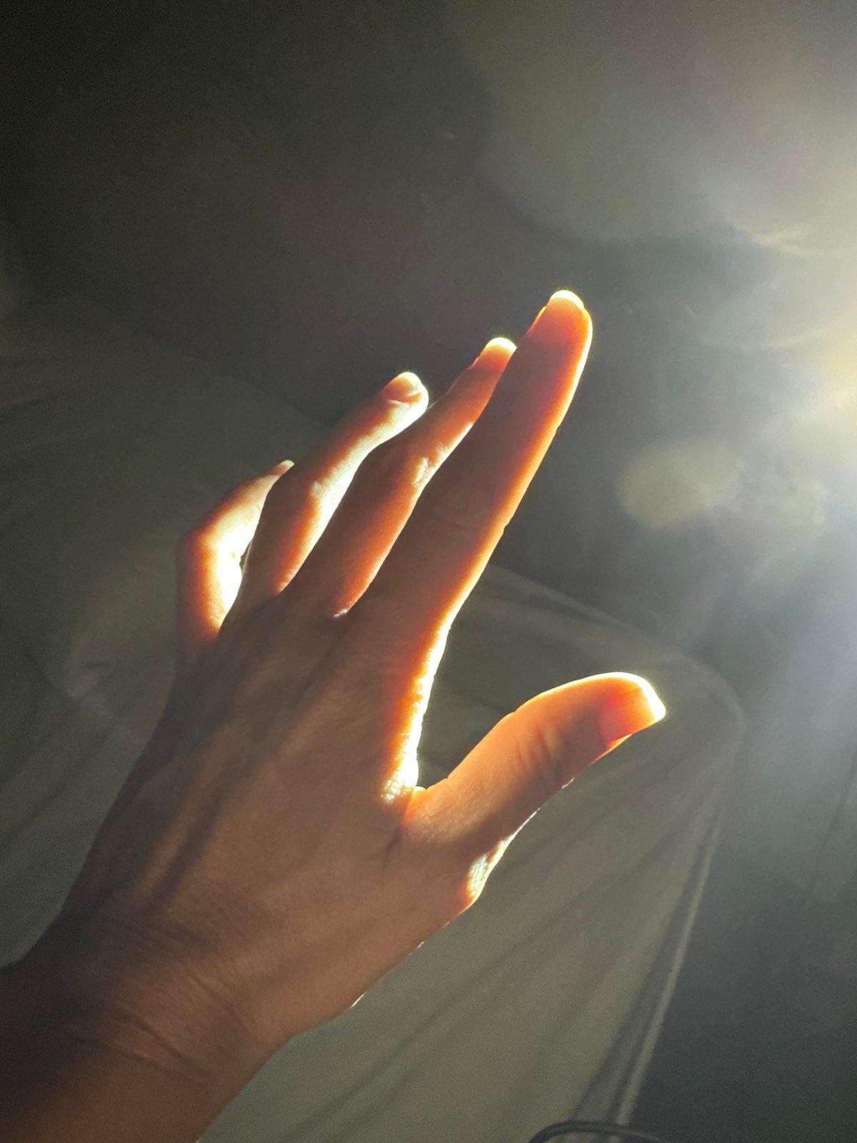 Hand reaches toward sunlight in Indonesian bedroom