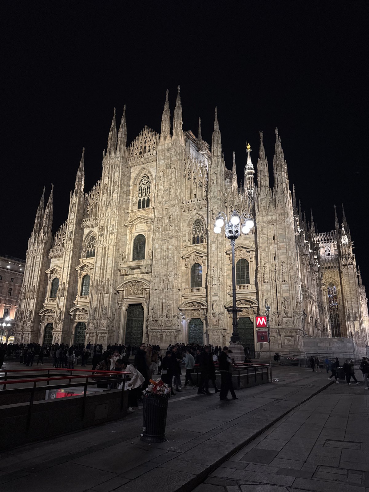 Evening tourists photograph illuminated Milan Cathedral and landmarks
