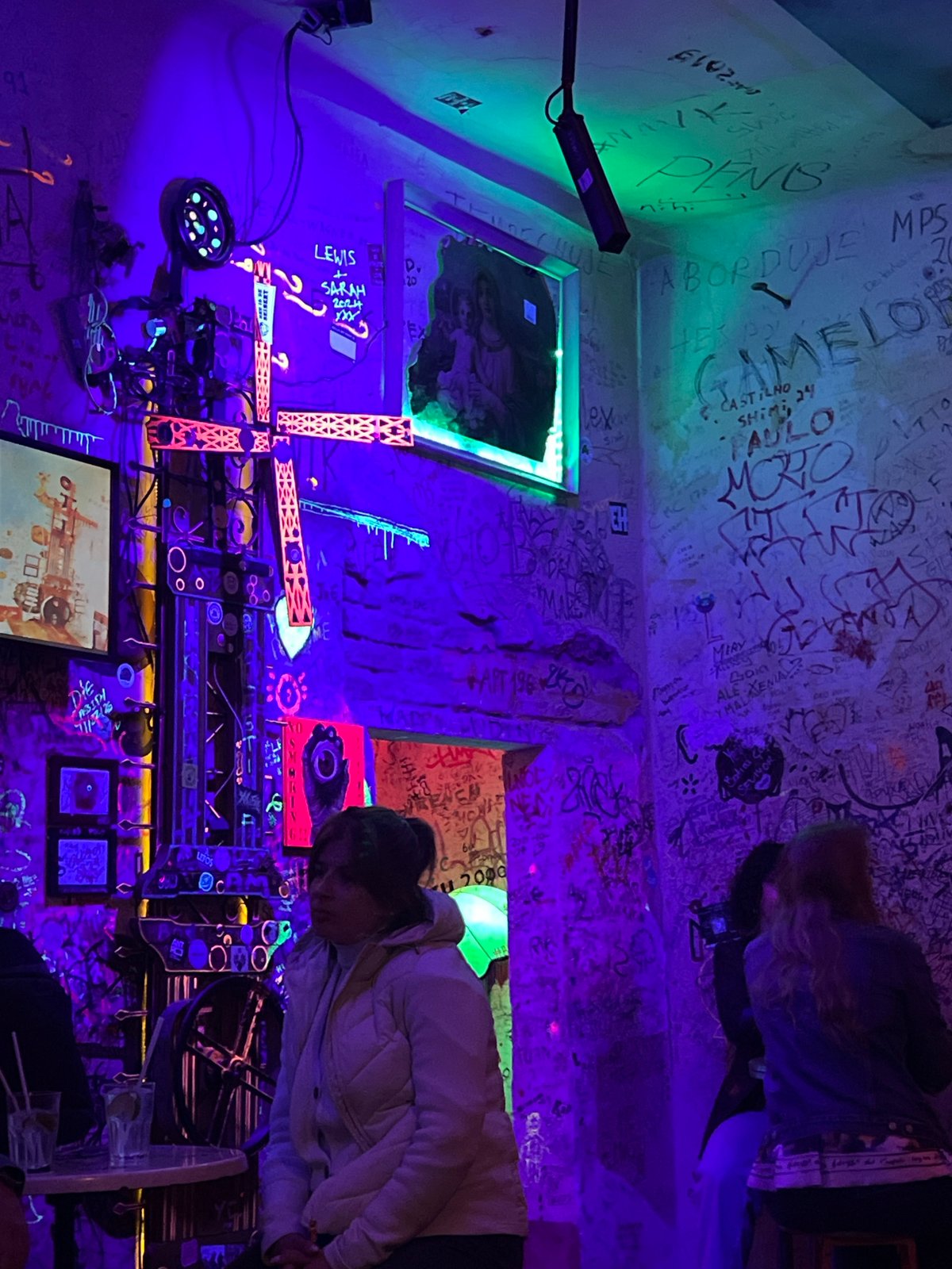 Woman walks through neon-lit graffiti bar in Budapest