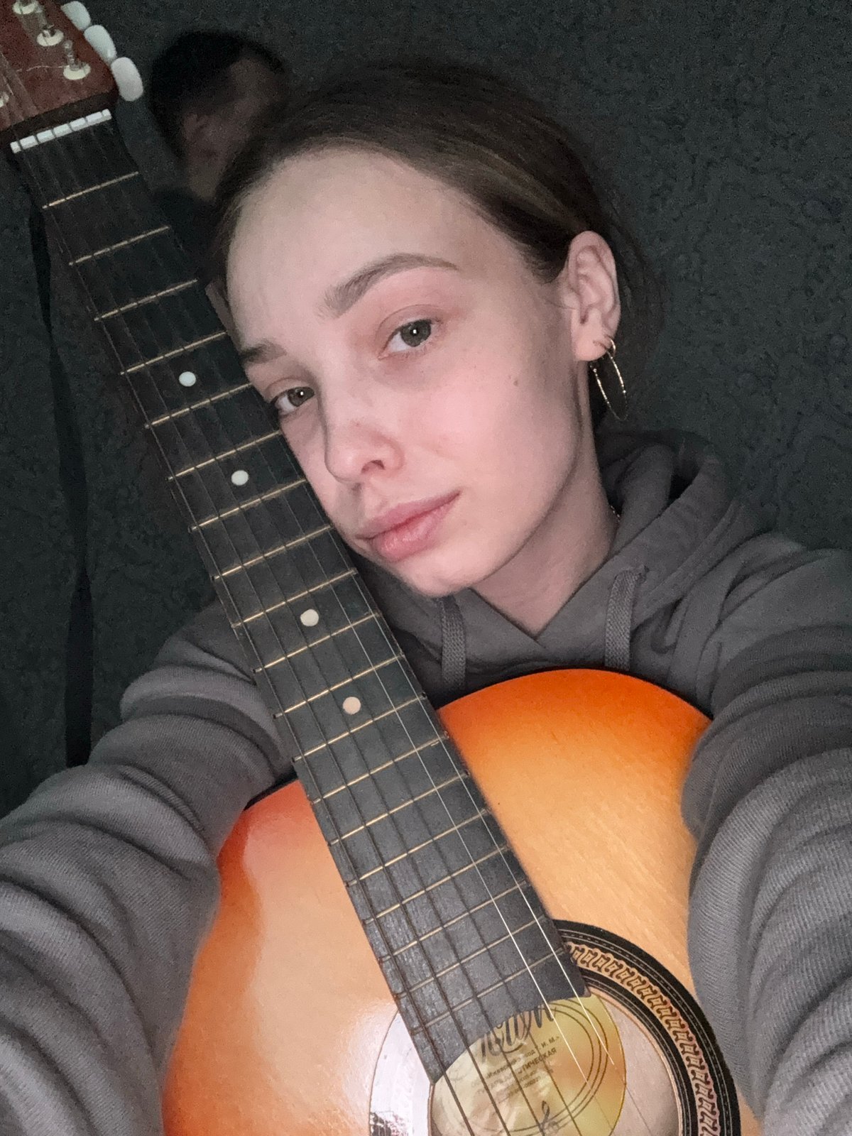 Woman poses with acoustic guitar in Russian indoor session