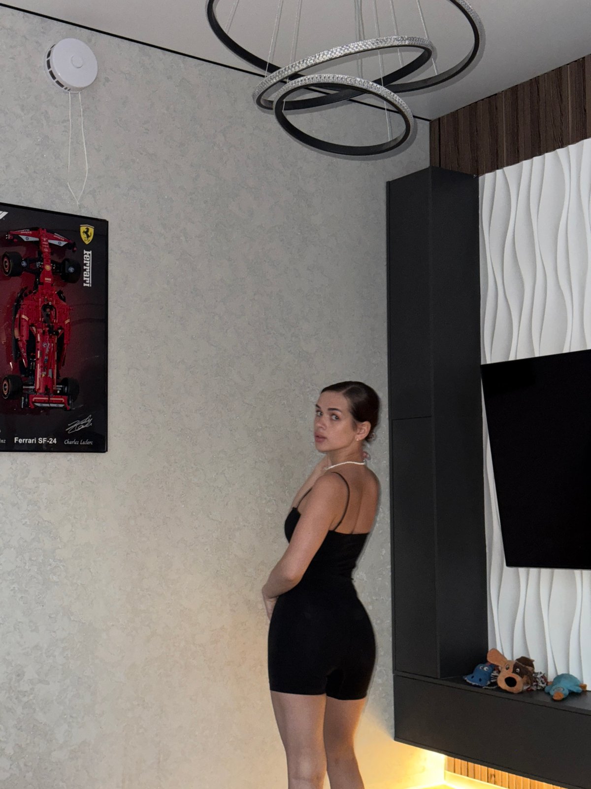 Woman poses with cat in Russian home featuring Ferrari poster