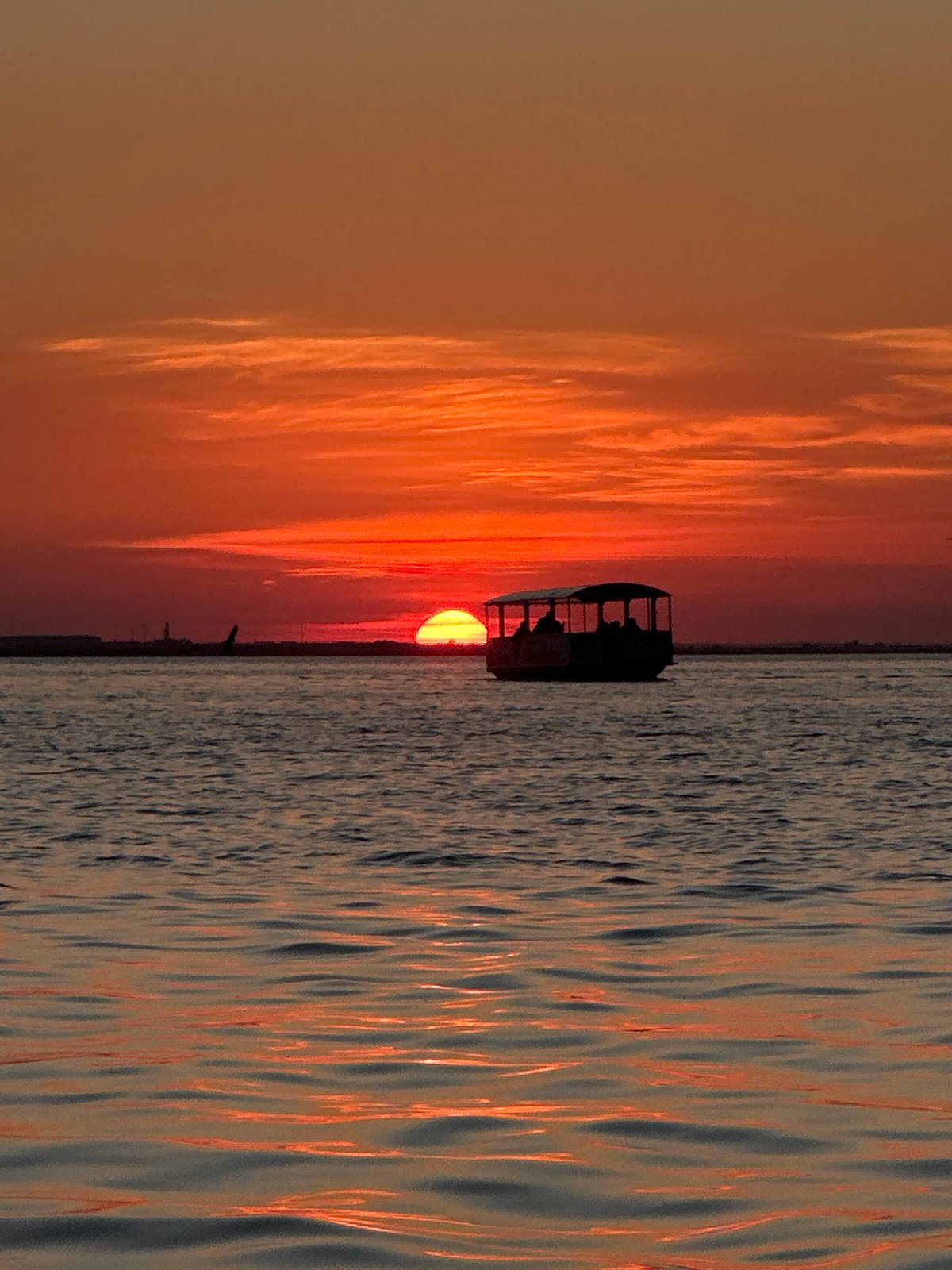Boat silhouetted against fiery sunset on Kokshetau waters