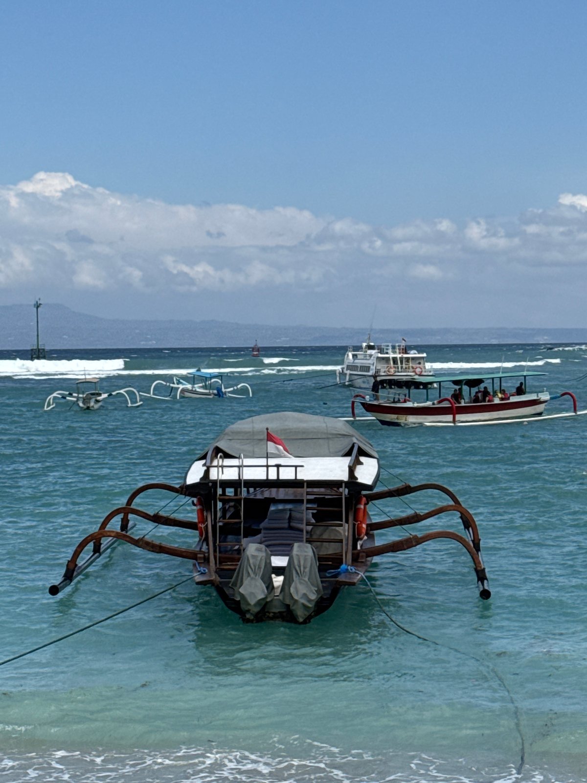 Quiet morning on the Manggis coast: boats, bikes, and a beach village