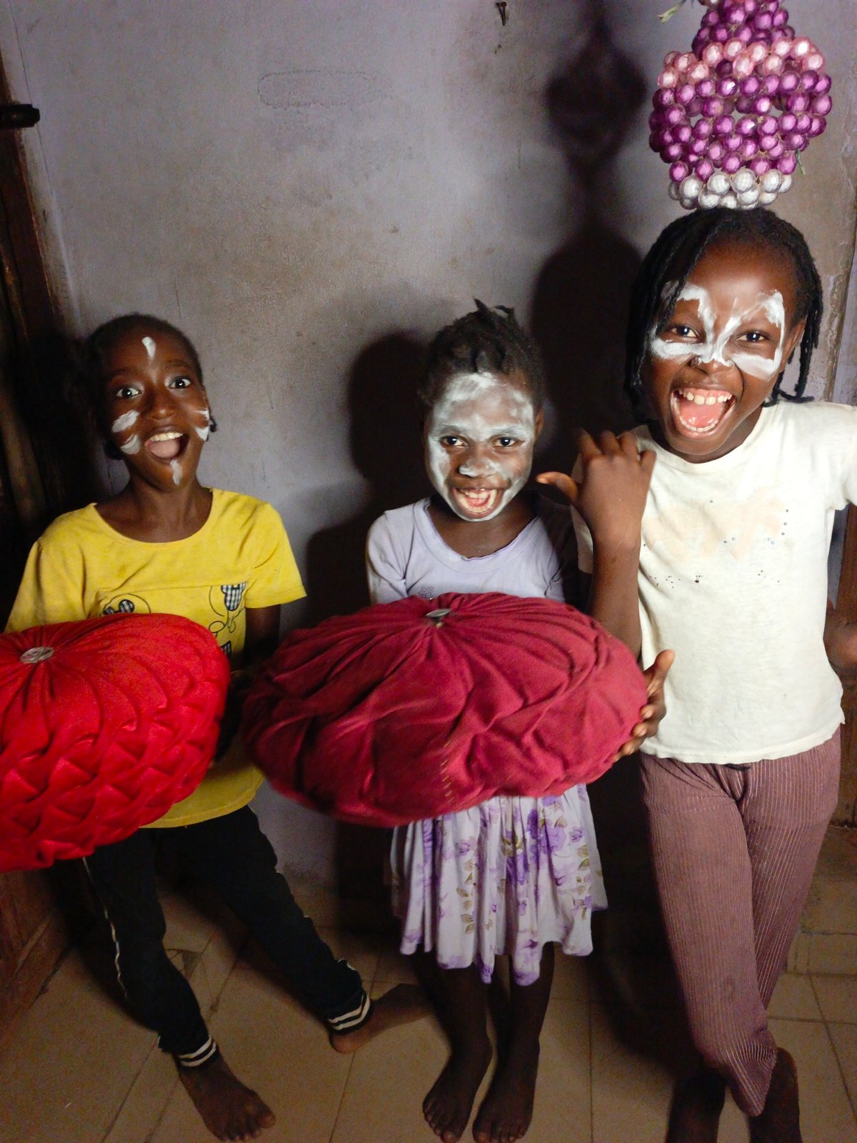 Children celebrate with traditional white face paint indoors