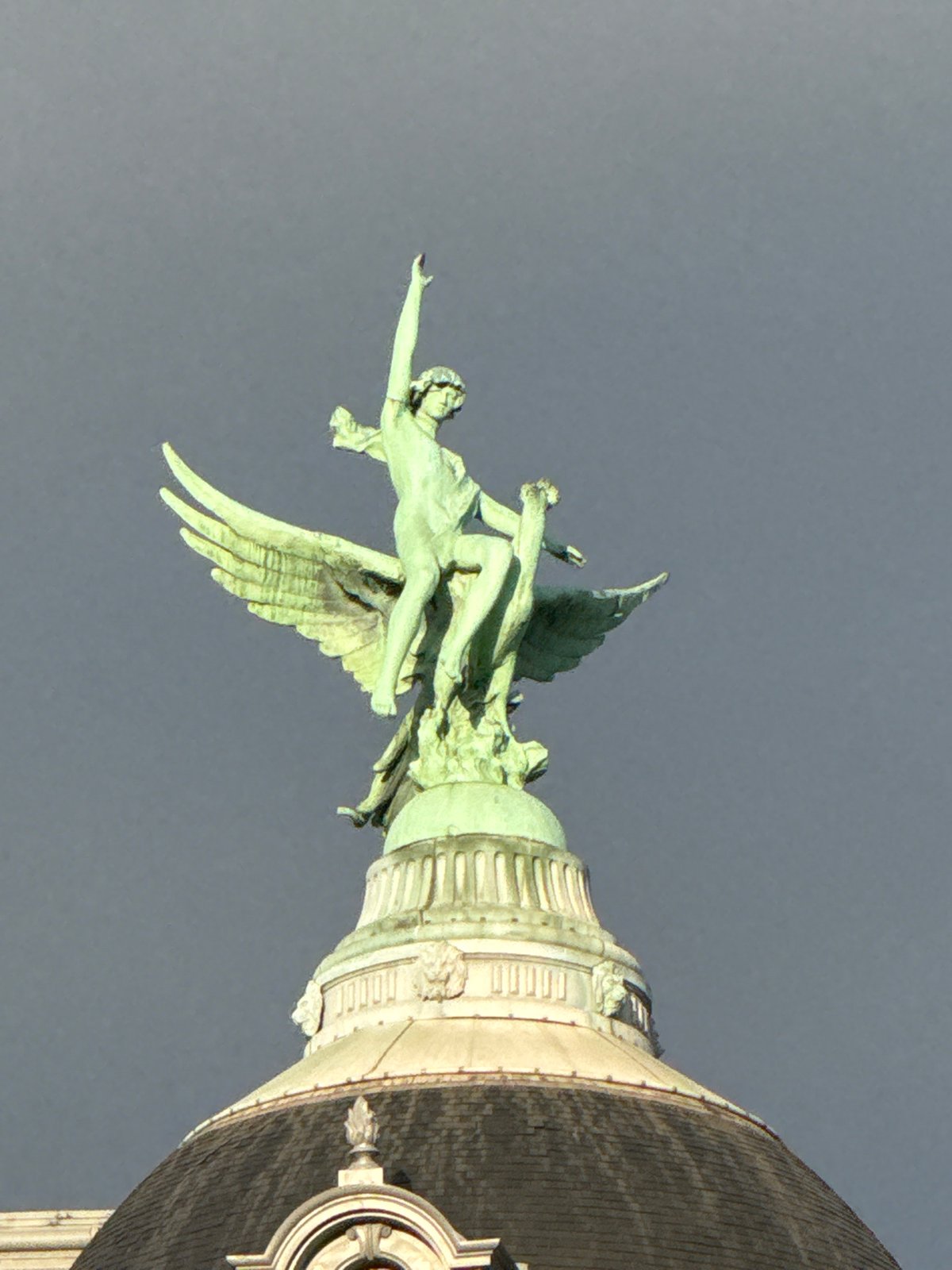 Green angelic statue observed on classical Paris architecture