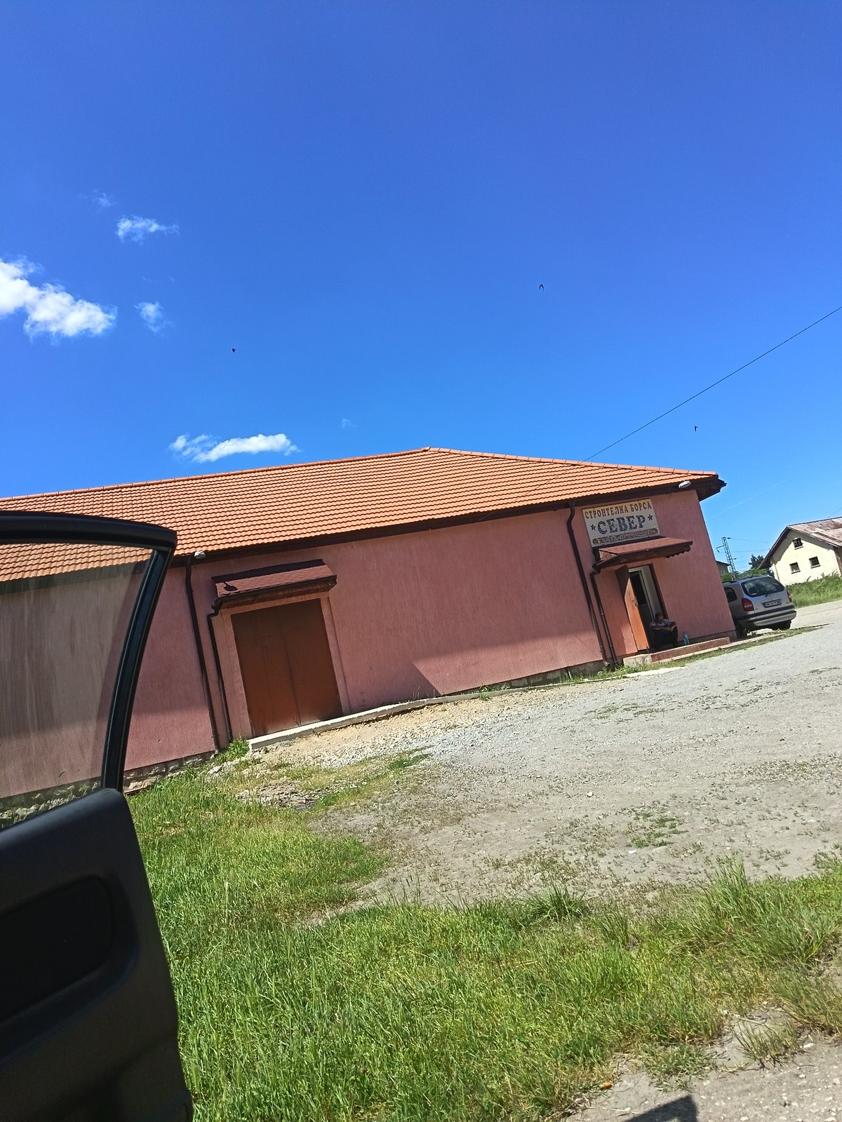 Person relaxes in car near building in Drenovets