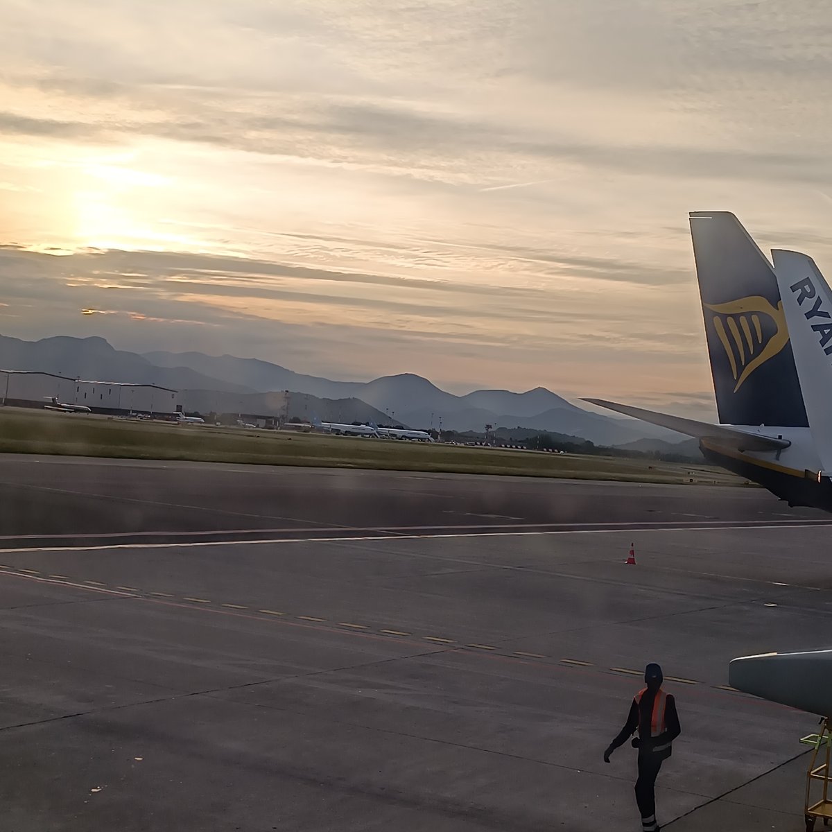 Airport dawn scene observed with warm lighting, layered clouds