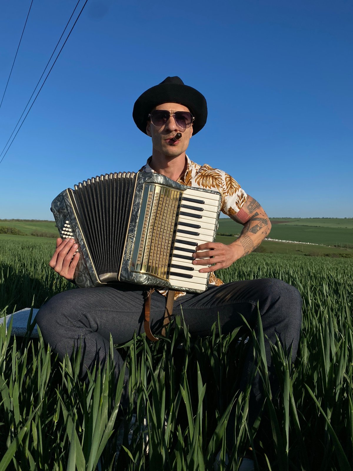 Accordion player performs in Bulgarian field under blue skies