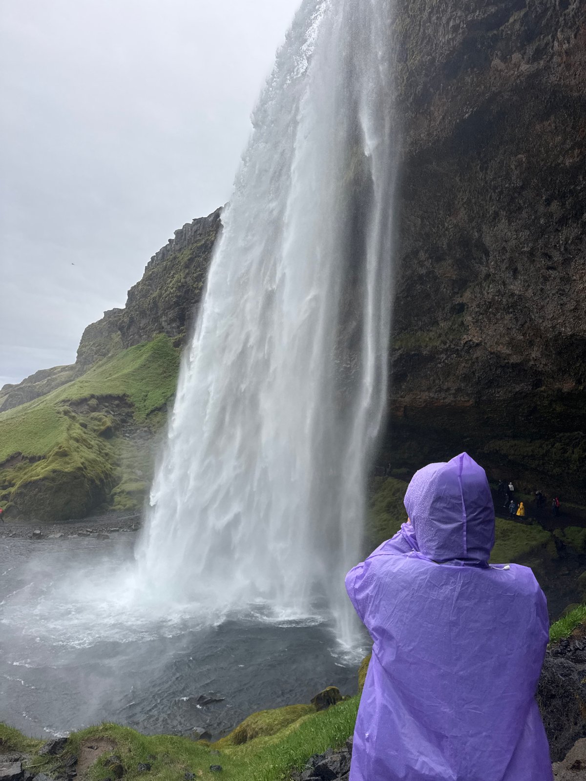 Tourists visit Seljalandsfoss waterfall on overcast Iceland morning