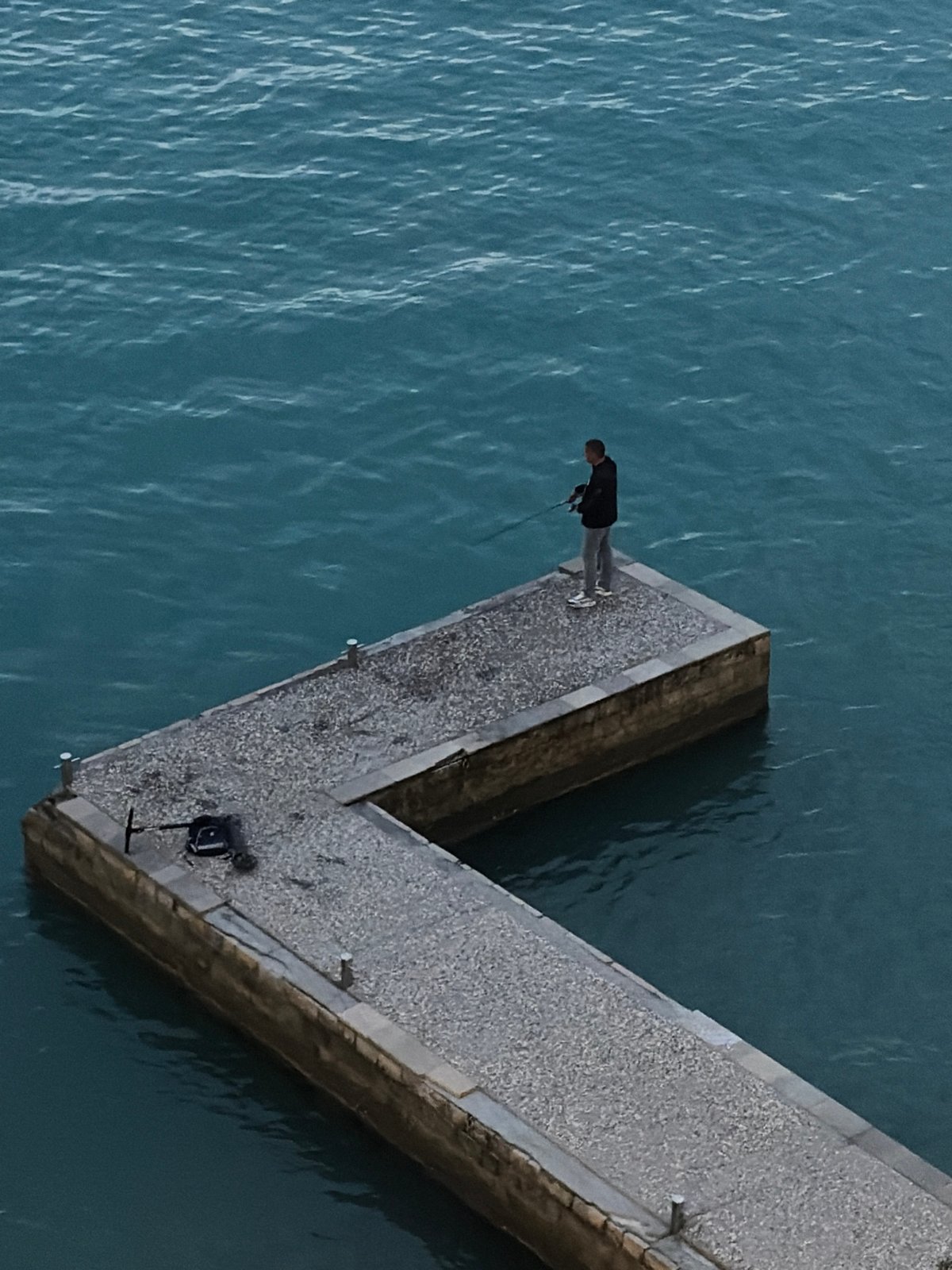 Solitary figure observed on Budva pier at dusk