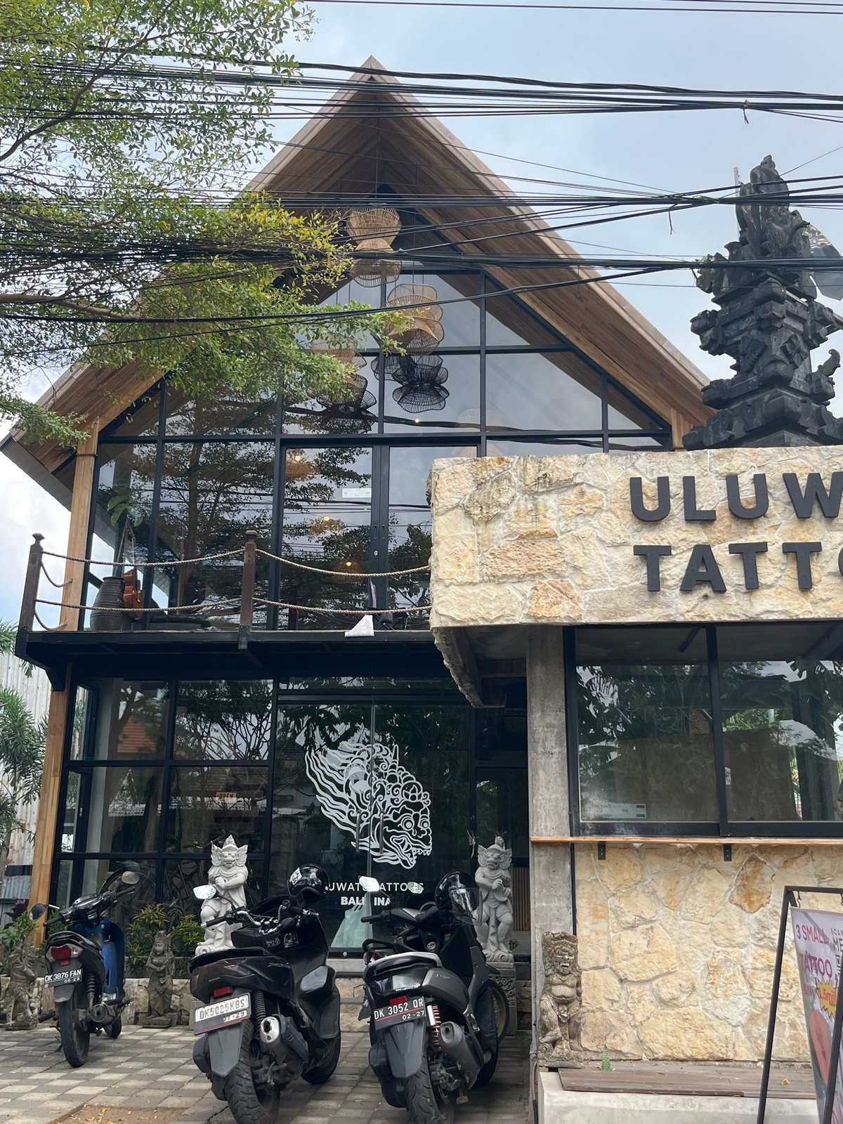 Tattoo parlor exterior and Balinese statuary documented in Kuta