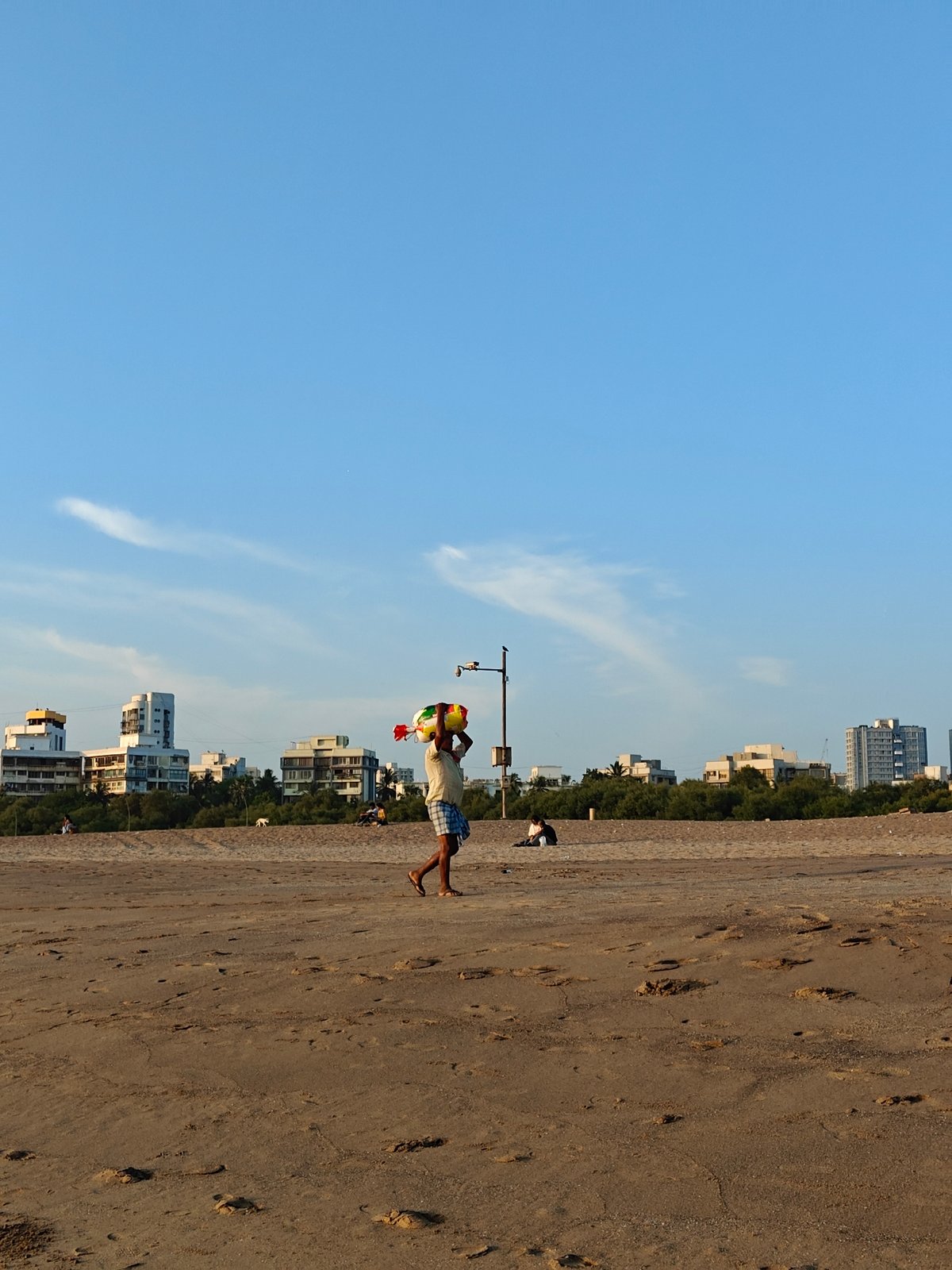 Beach vendors carry goods along Mumbai shoreline