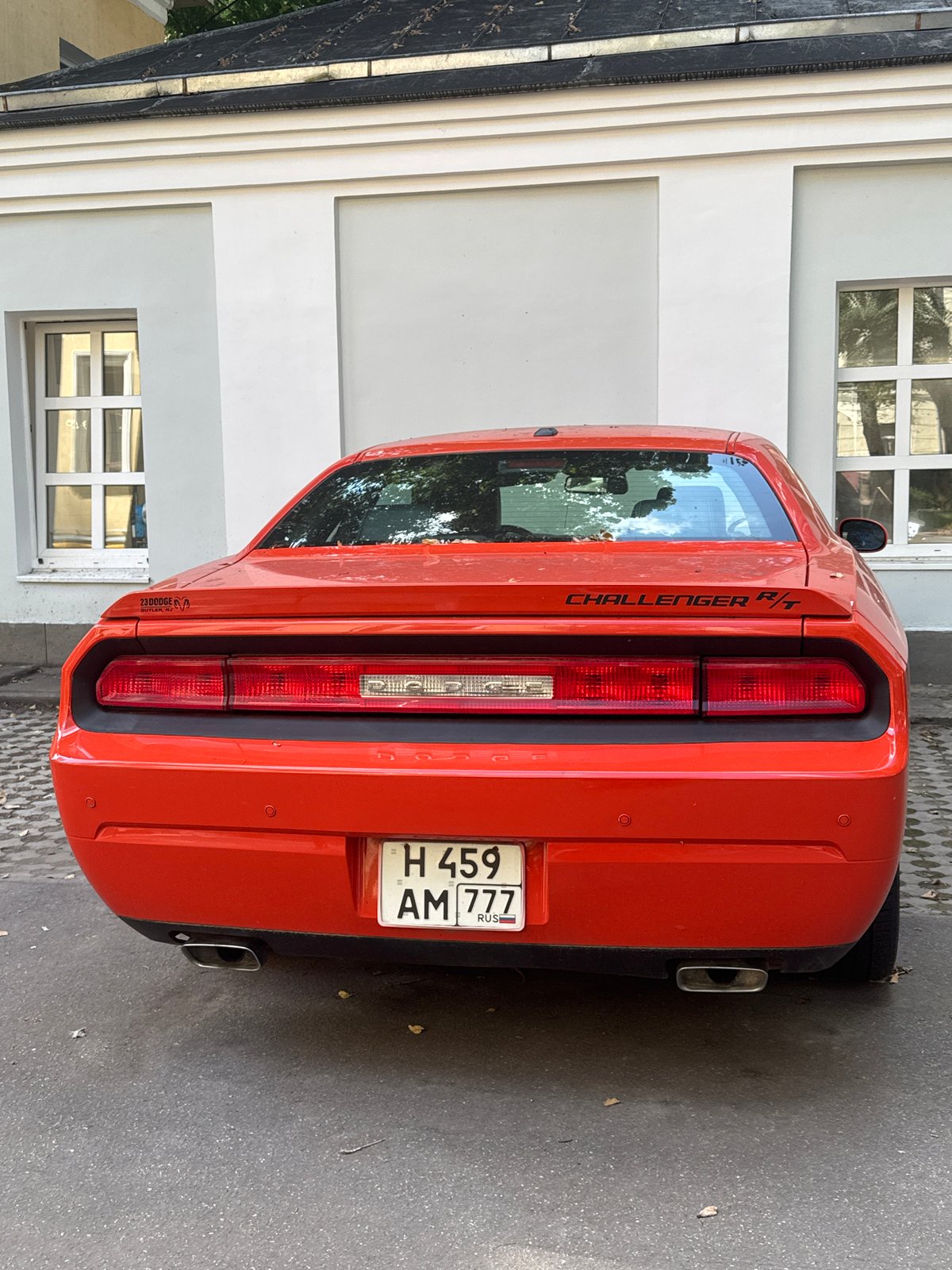 Red Dodge Challenger R/T parked near Moscow landmark, Sheltie in tow