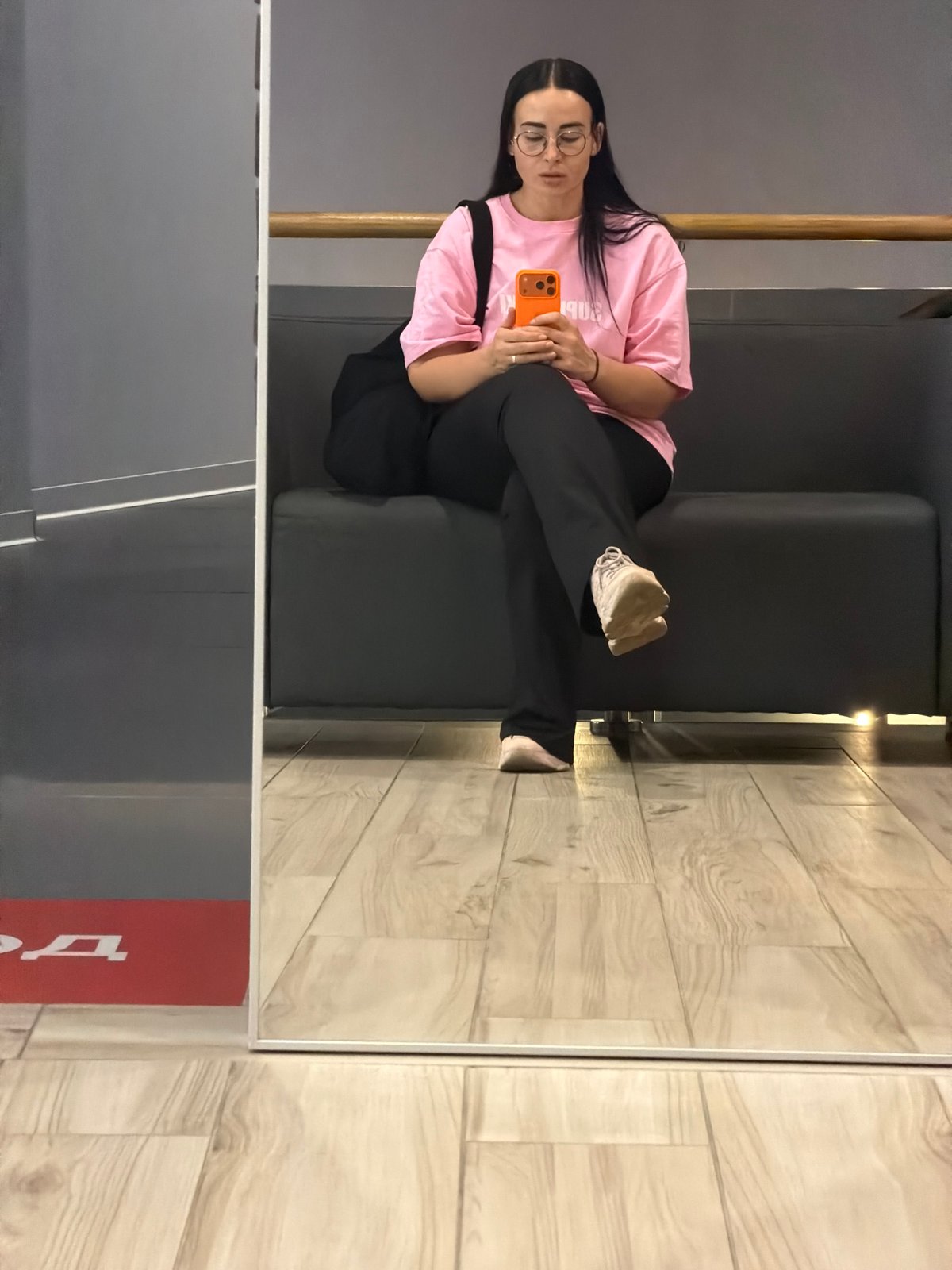 Woman with orange phone sits on sofa in Saint Petersburg