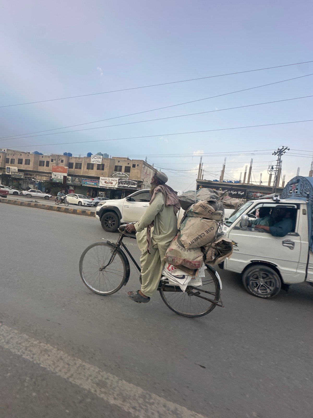 Cyclist transports cement bags on overloaded bicycle in Quetta