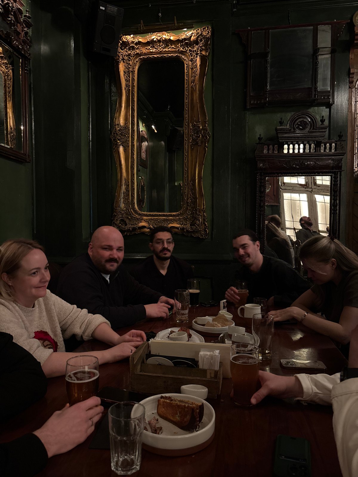 Six people gather around table in pub setting